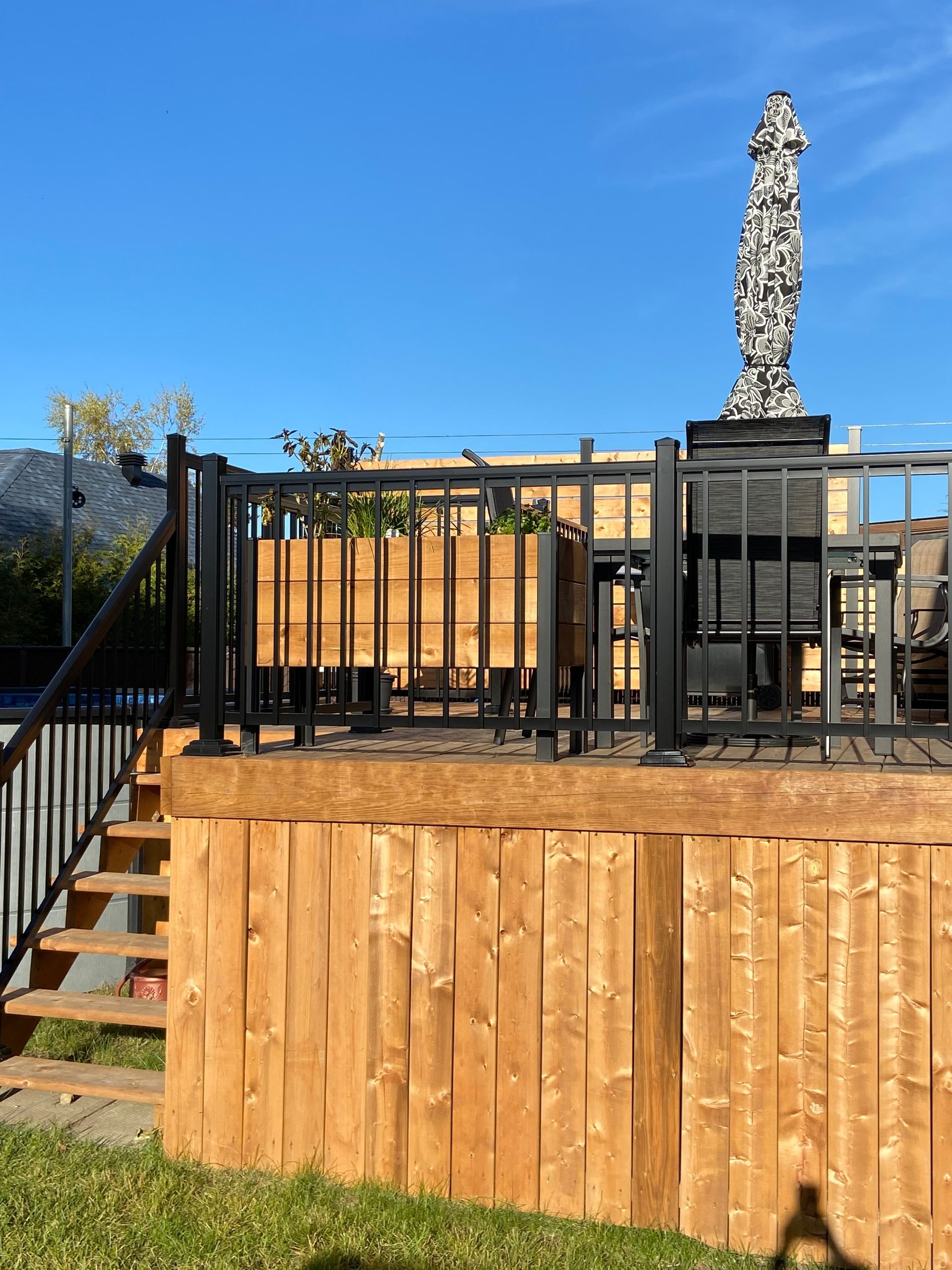 Une terrasse en bois avec des escaliers et une balustrade noire