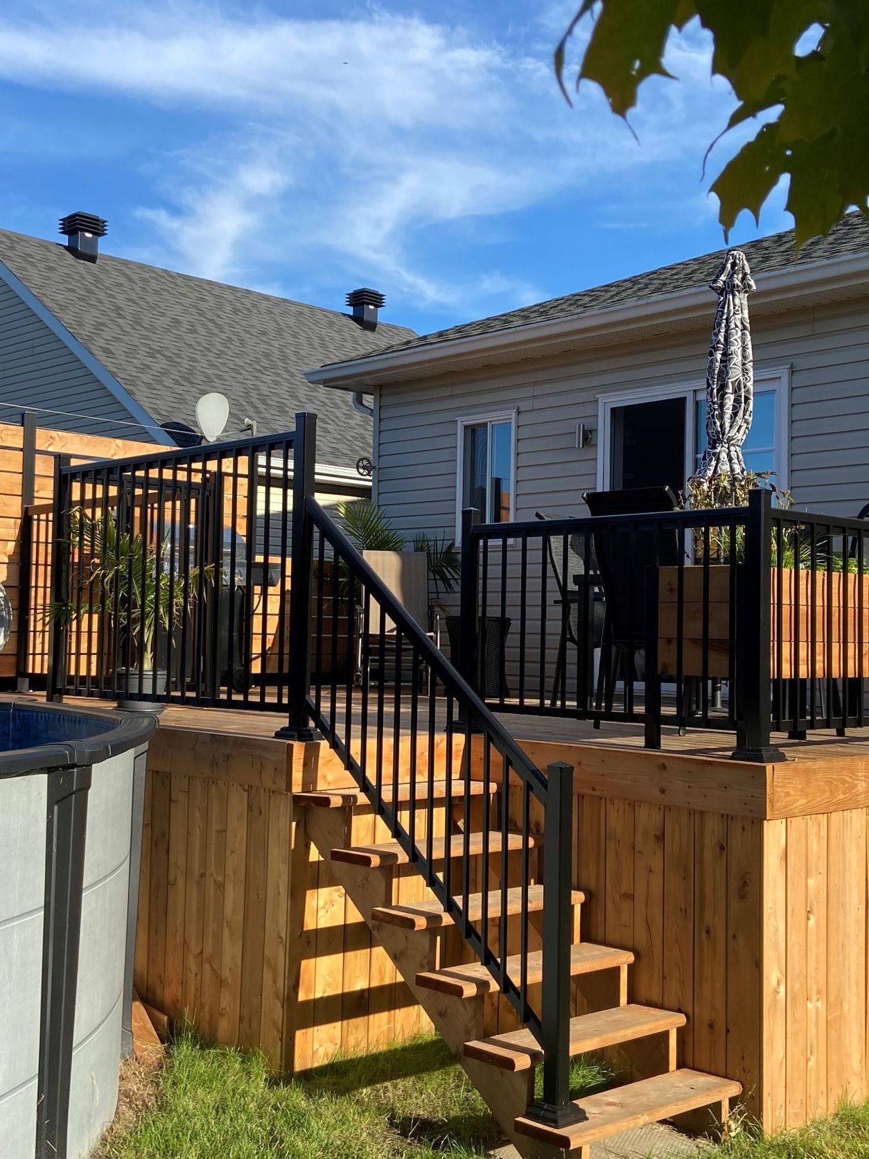 Une terrasse en bois avec des escaliers qui y mènent et une maison en arrière-plan.