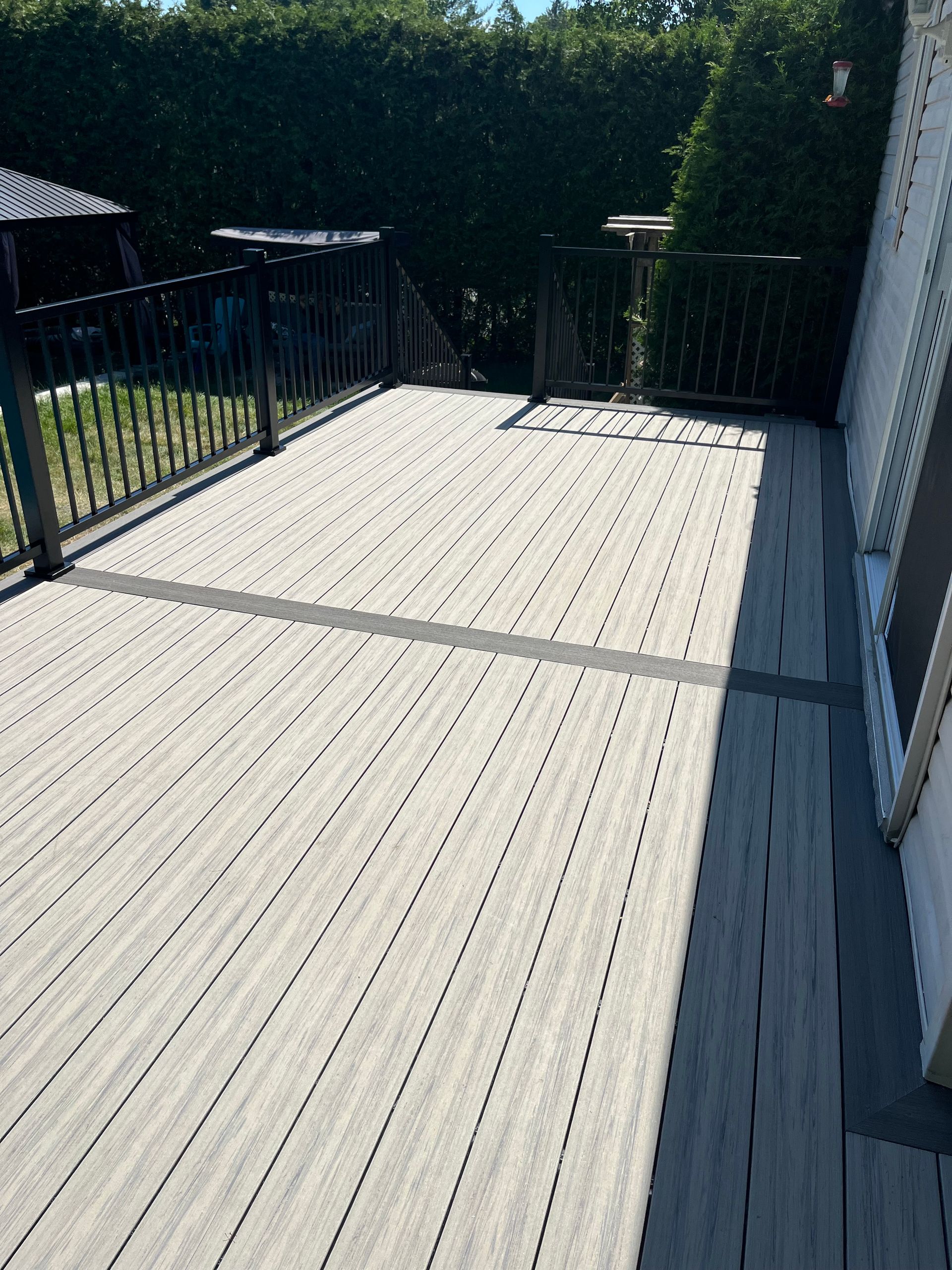Une terrasse en bois avec une clôture et des arbres en arrière-plan.