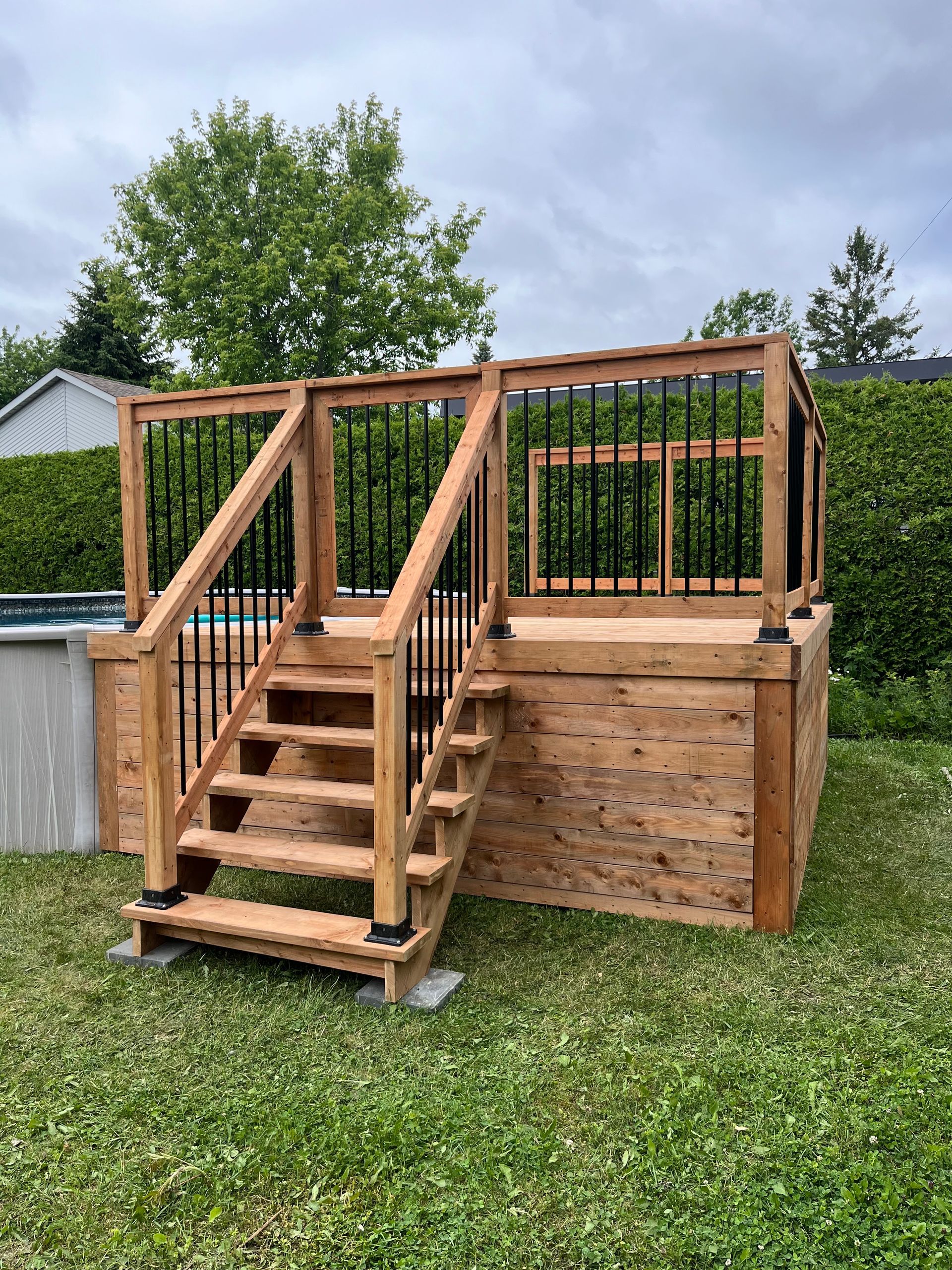 Une terrasse en bois avec des escaliers menant à côté d'une piscine.