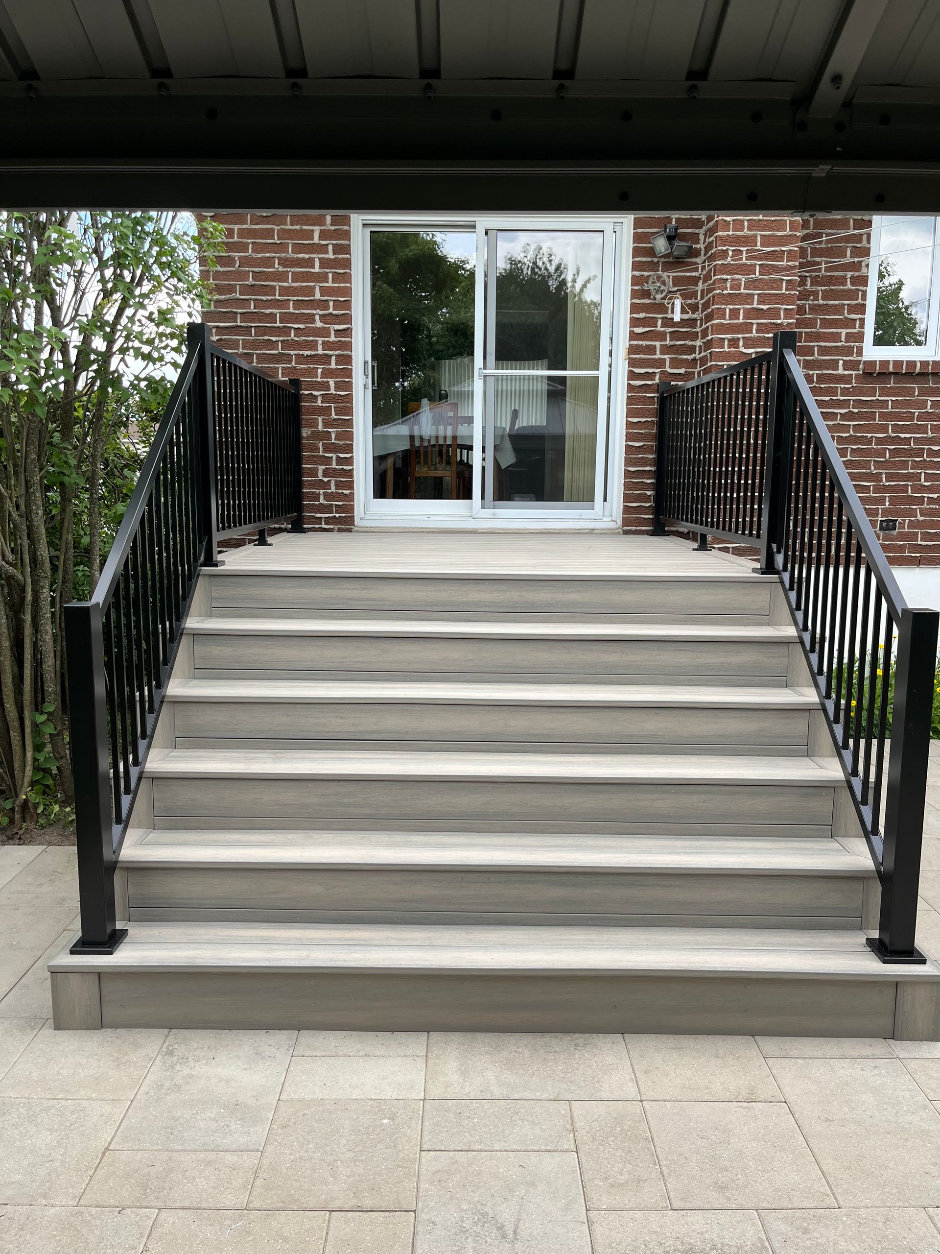 Un escalier menant à une maison en briques avec une balustrade noire.