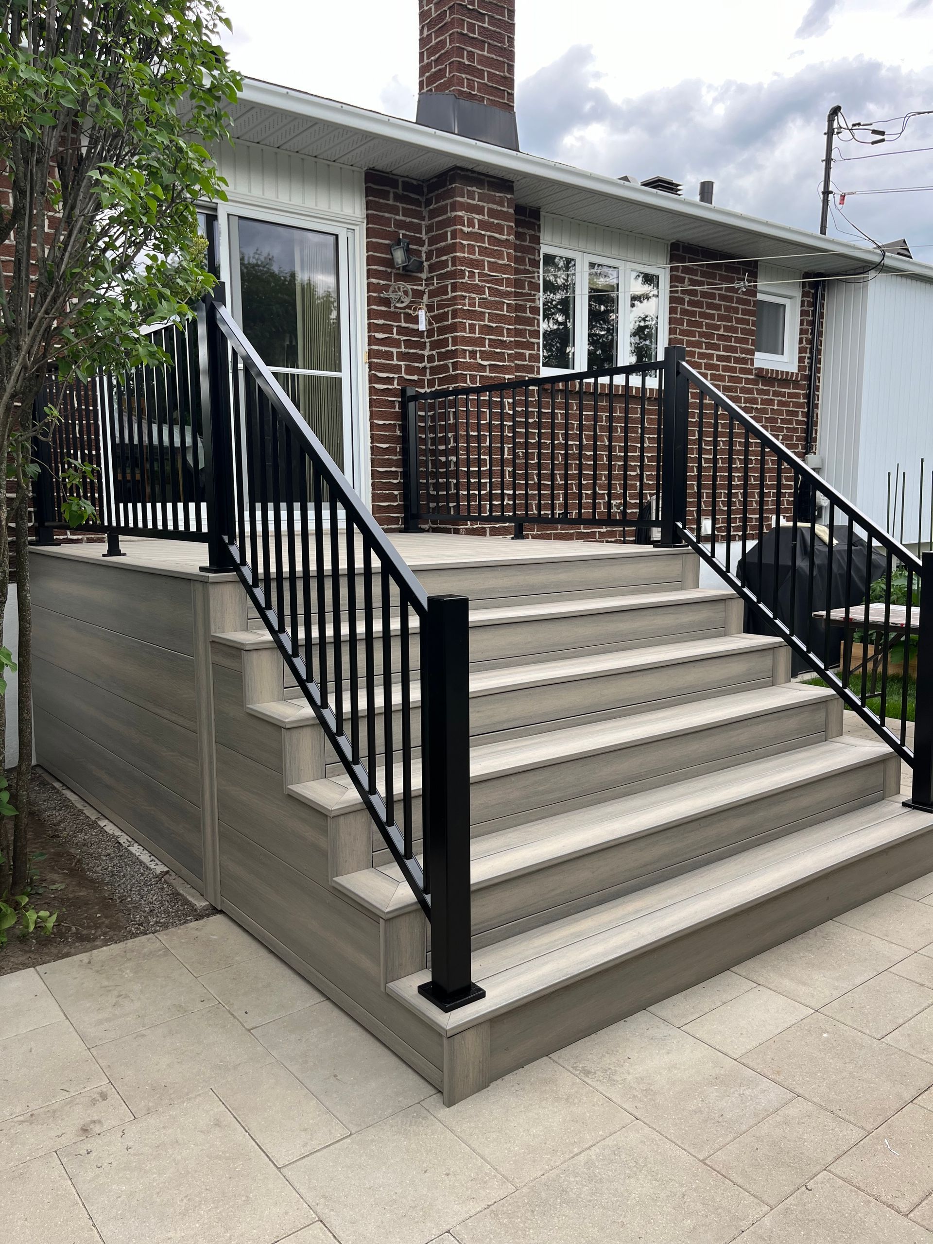 Une terrasse avec des escaliers qui y mènent et une balustrade noire.