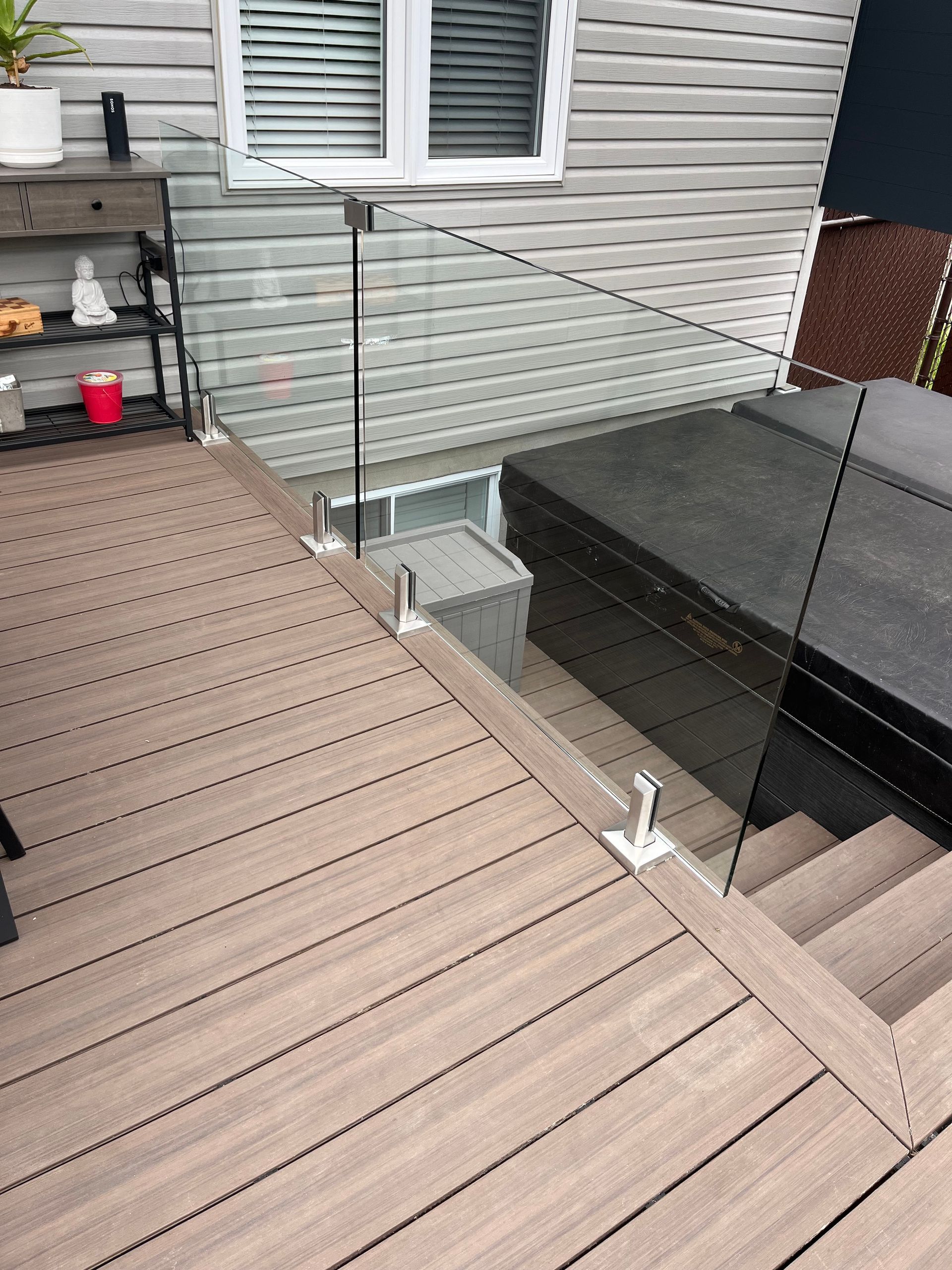 Une terrasse en bois avec escalier et garde-corps en verre.
