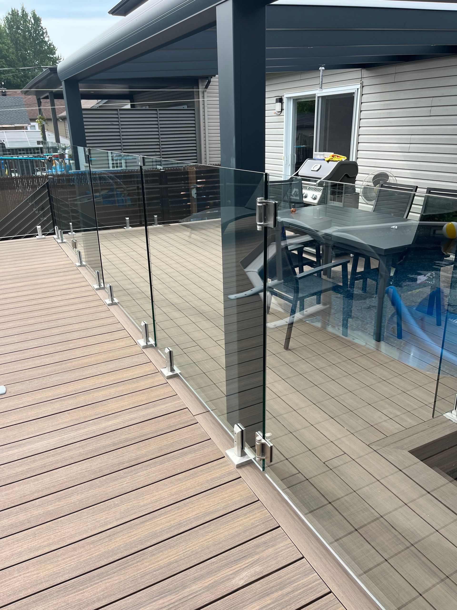 Une terrasse avec une balustrade en verre et une table et des chaises dessus