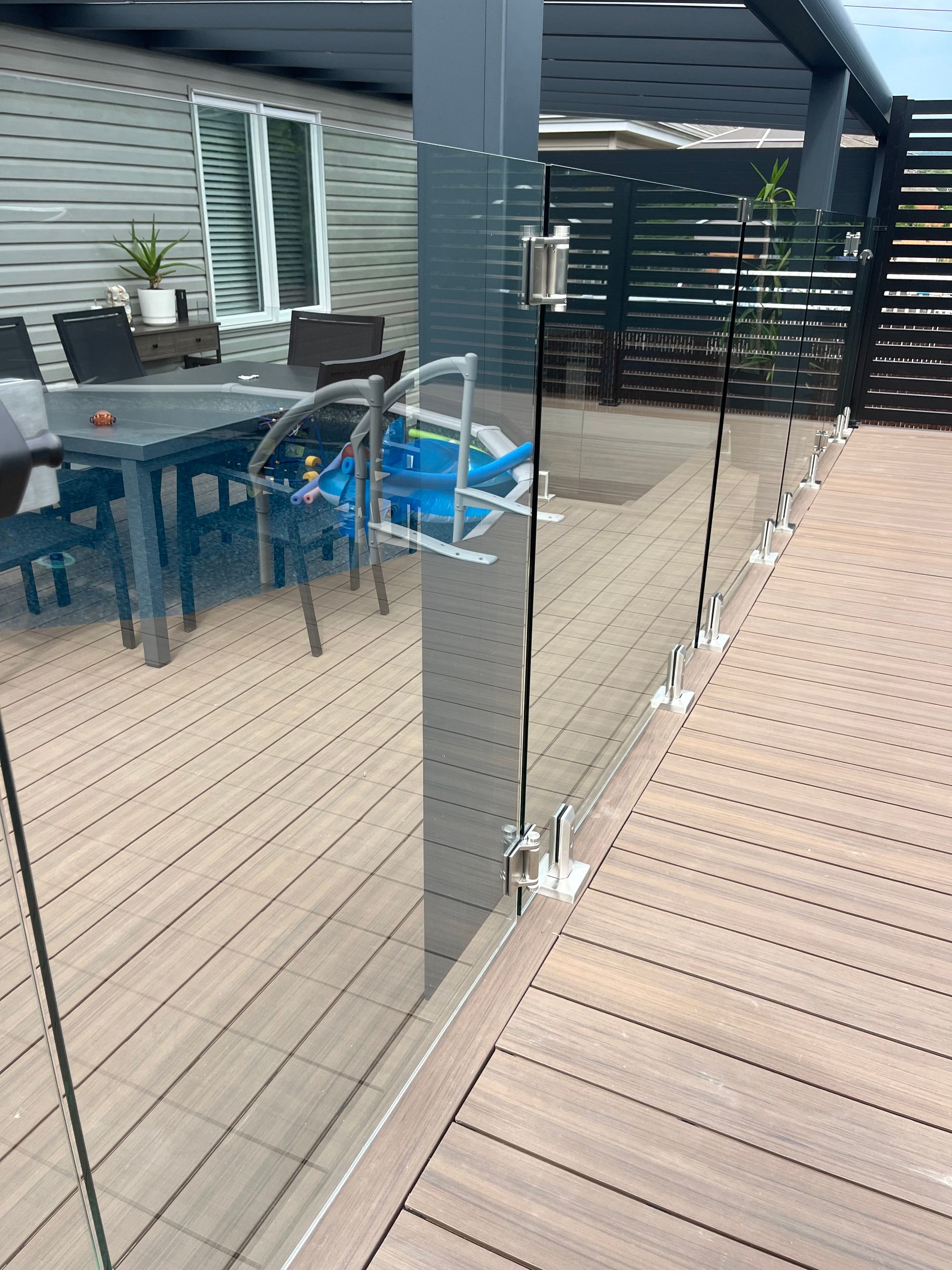Une terrasse avec une balustrade en verre et une table et des chaises dessus.
