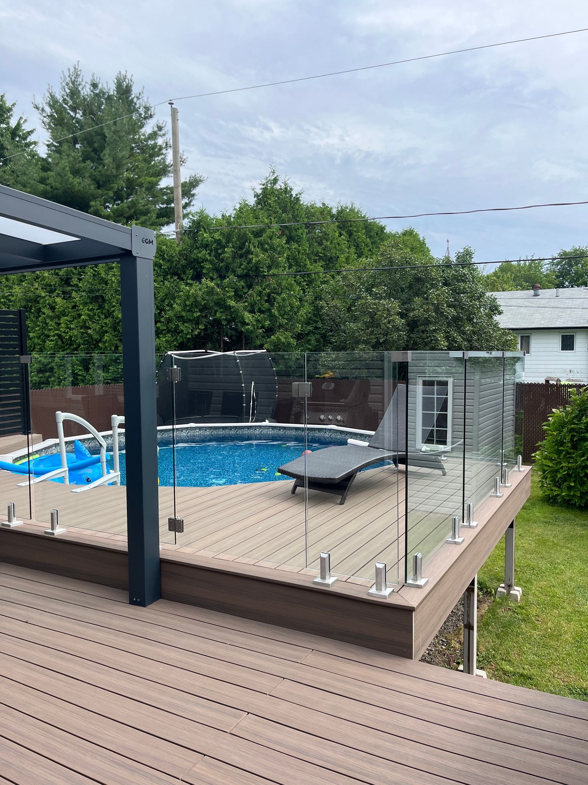 Une piscine est entourée d'une balustrade en verre sur une terrasse.