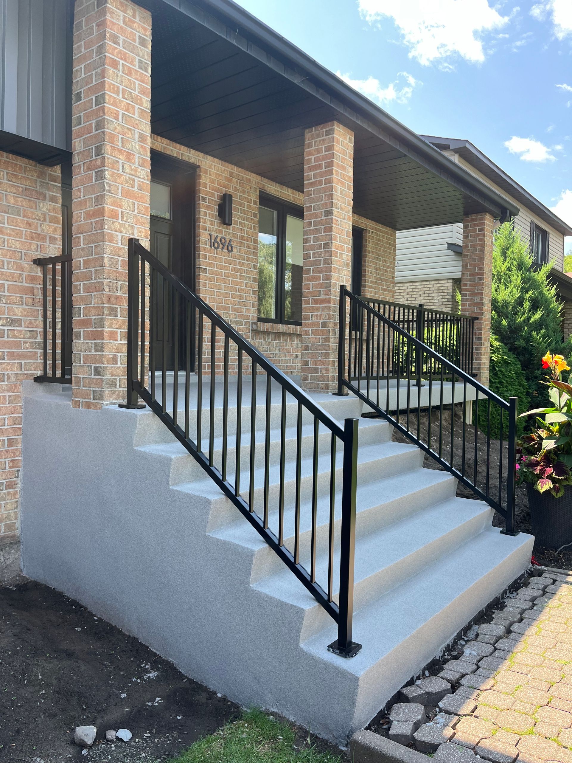 Une maison en briques avec des escaliers et une balustrade noire
