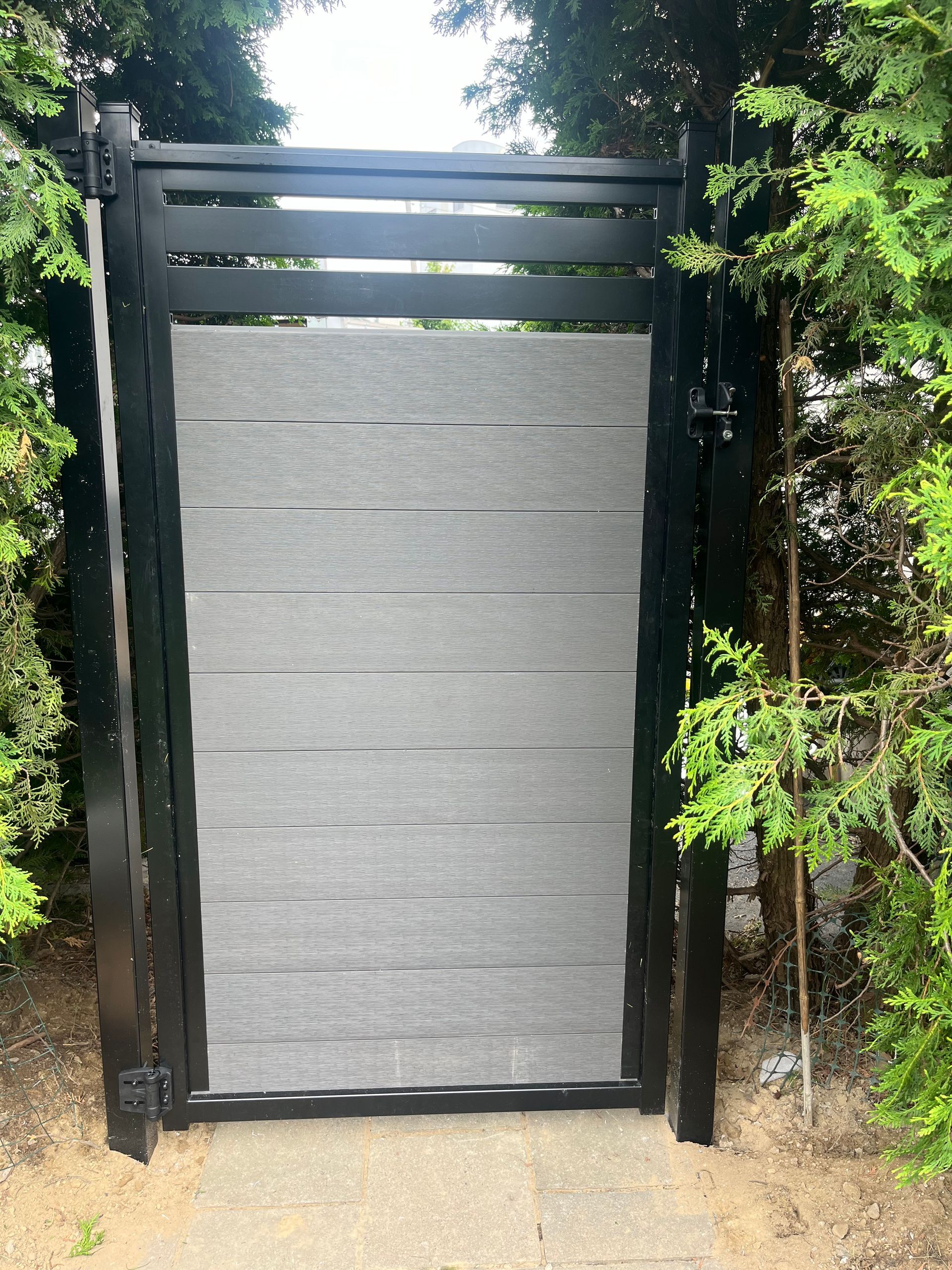 Un portail noir et gris est entouré d'arbres.