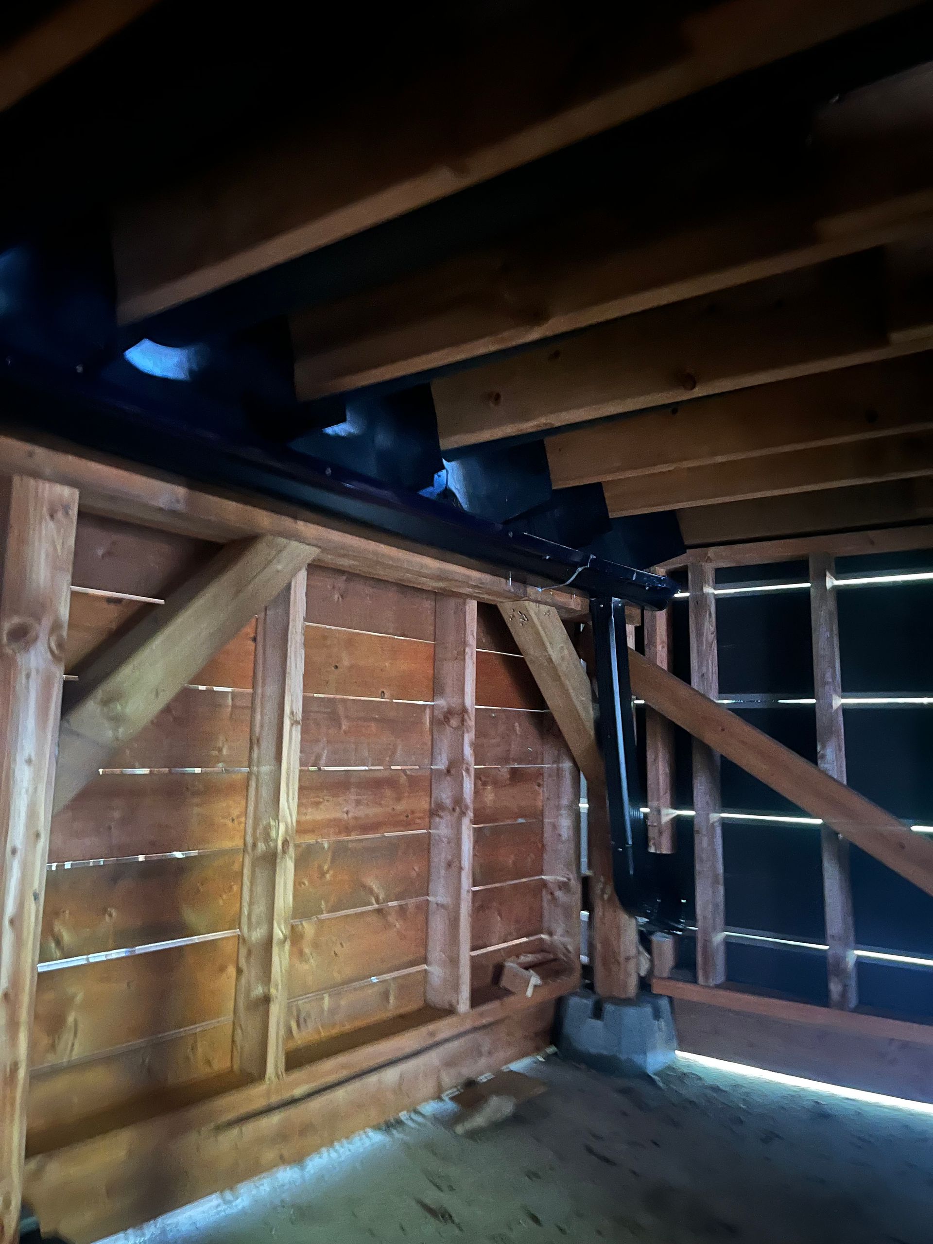 Une pièce sombre avec des poutres en bois et un tuyau noir