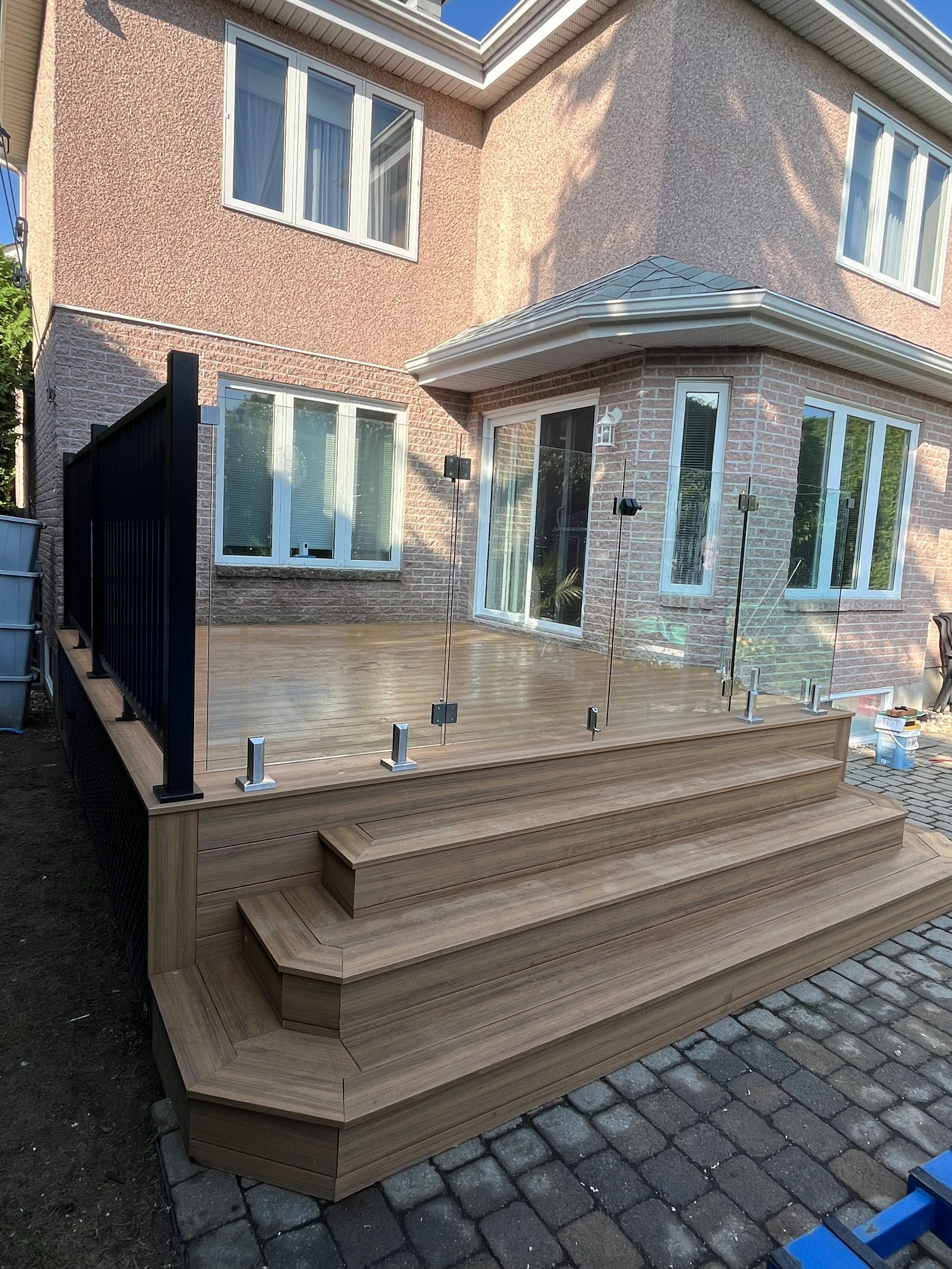 Une maison en briques avec une terrasse en bois et des escaliers devant.