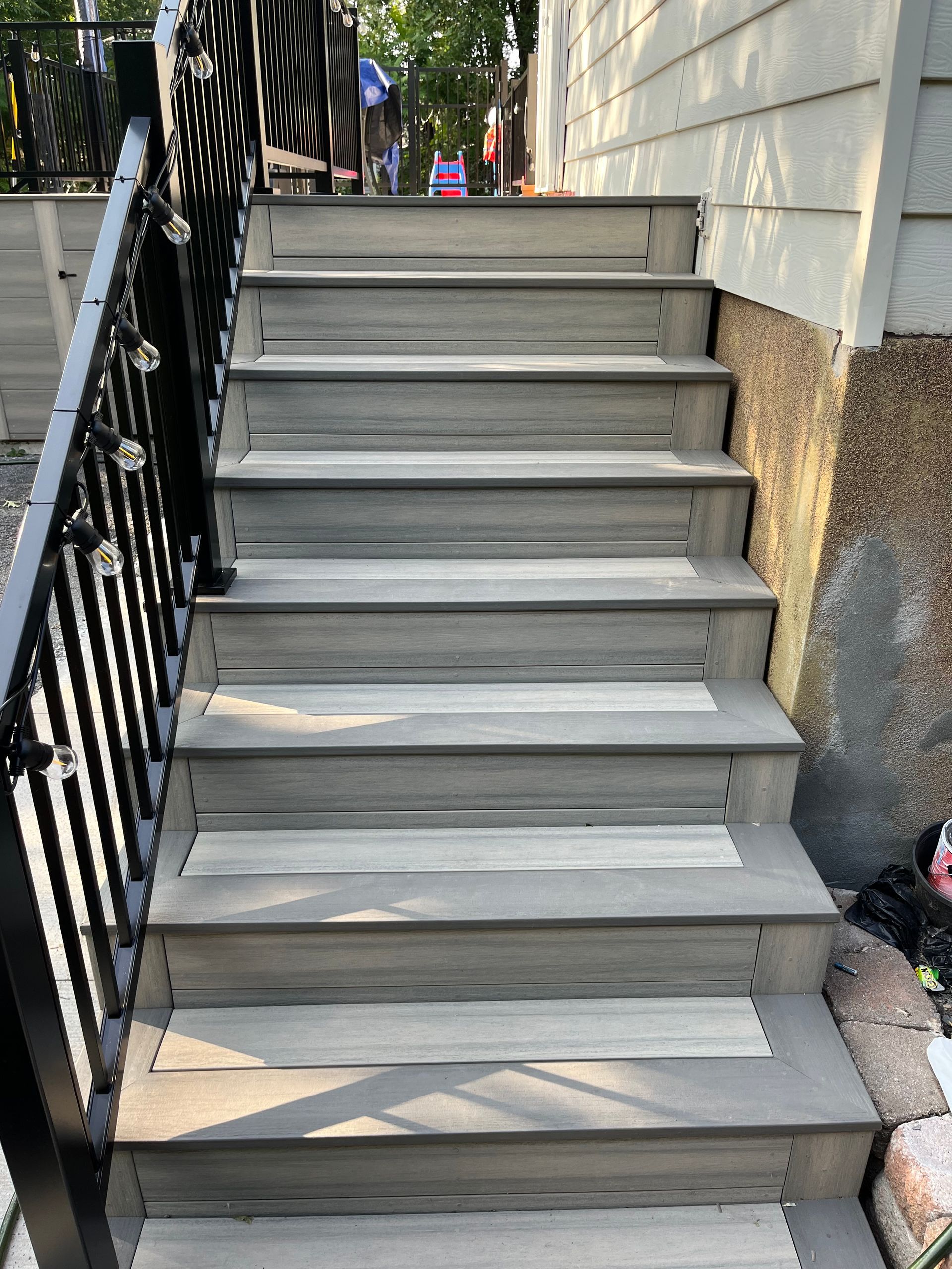 Un escalier menant à une maison avec une rampe noire.