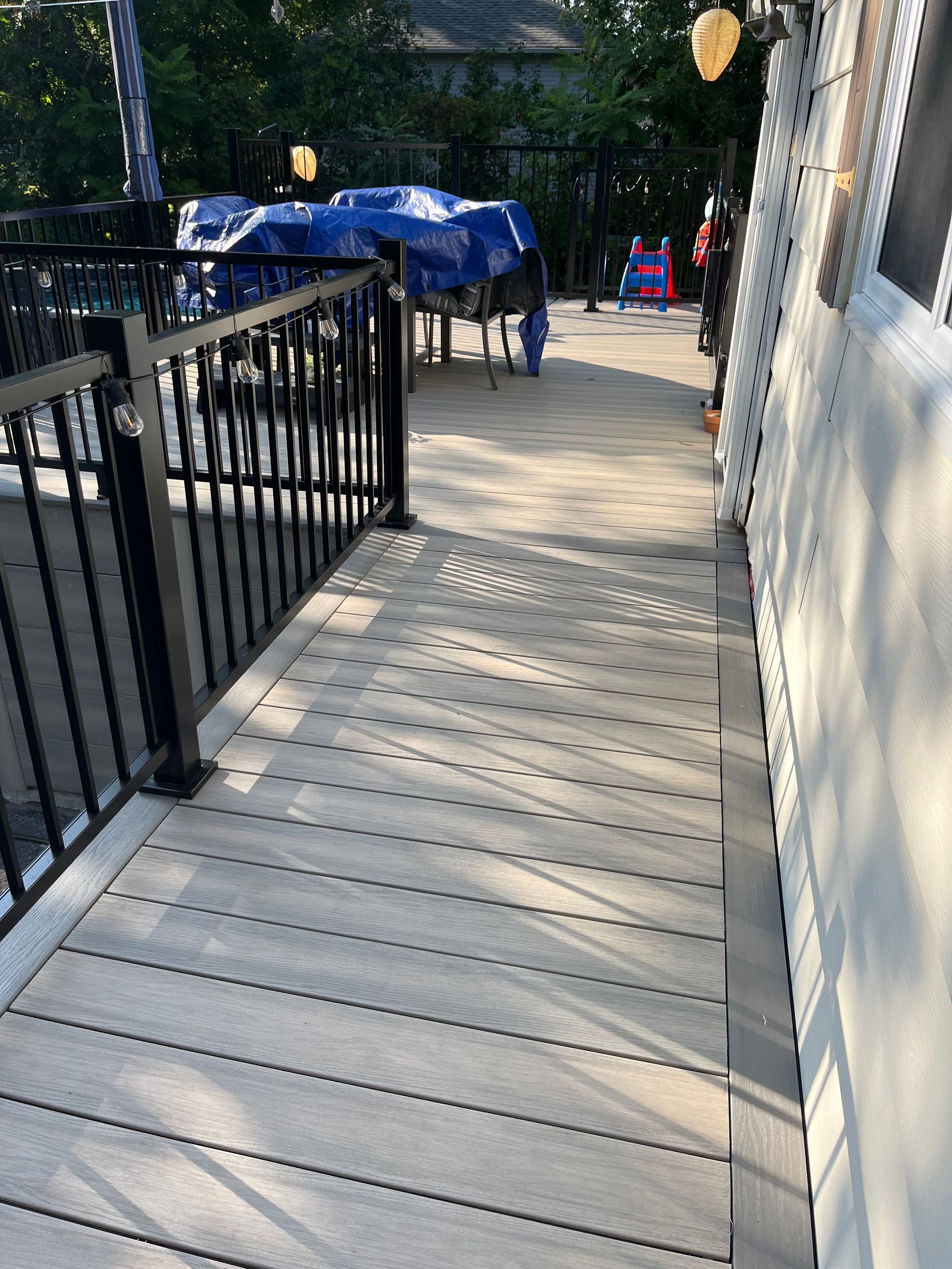 Une terrasse en bois avec une balustrade en métal et des escaliers qui y mènent.