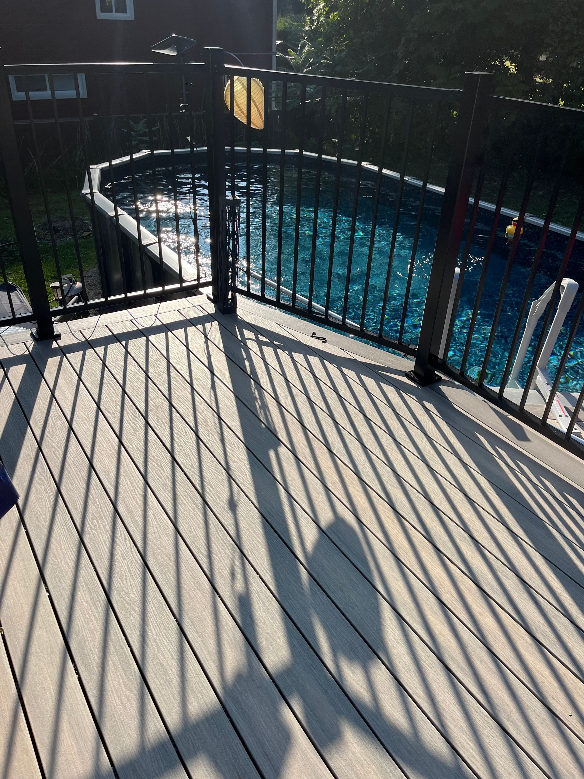 Une terrasse avec une clôture et une piscine en arrière-plan