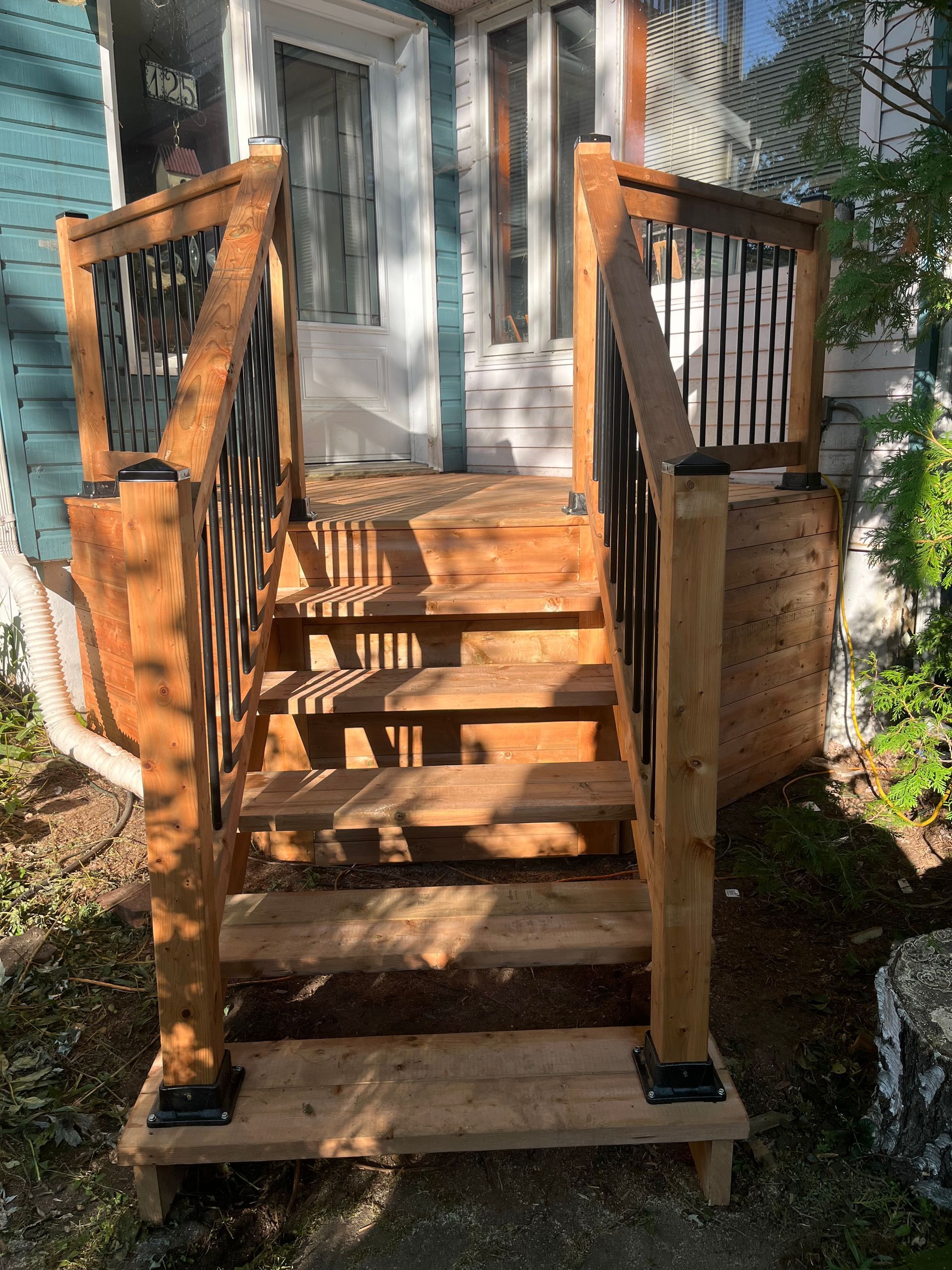 Une terrasse en bois avec des escaliers menant à la porte d'entrée d'une maison.