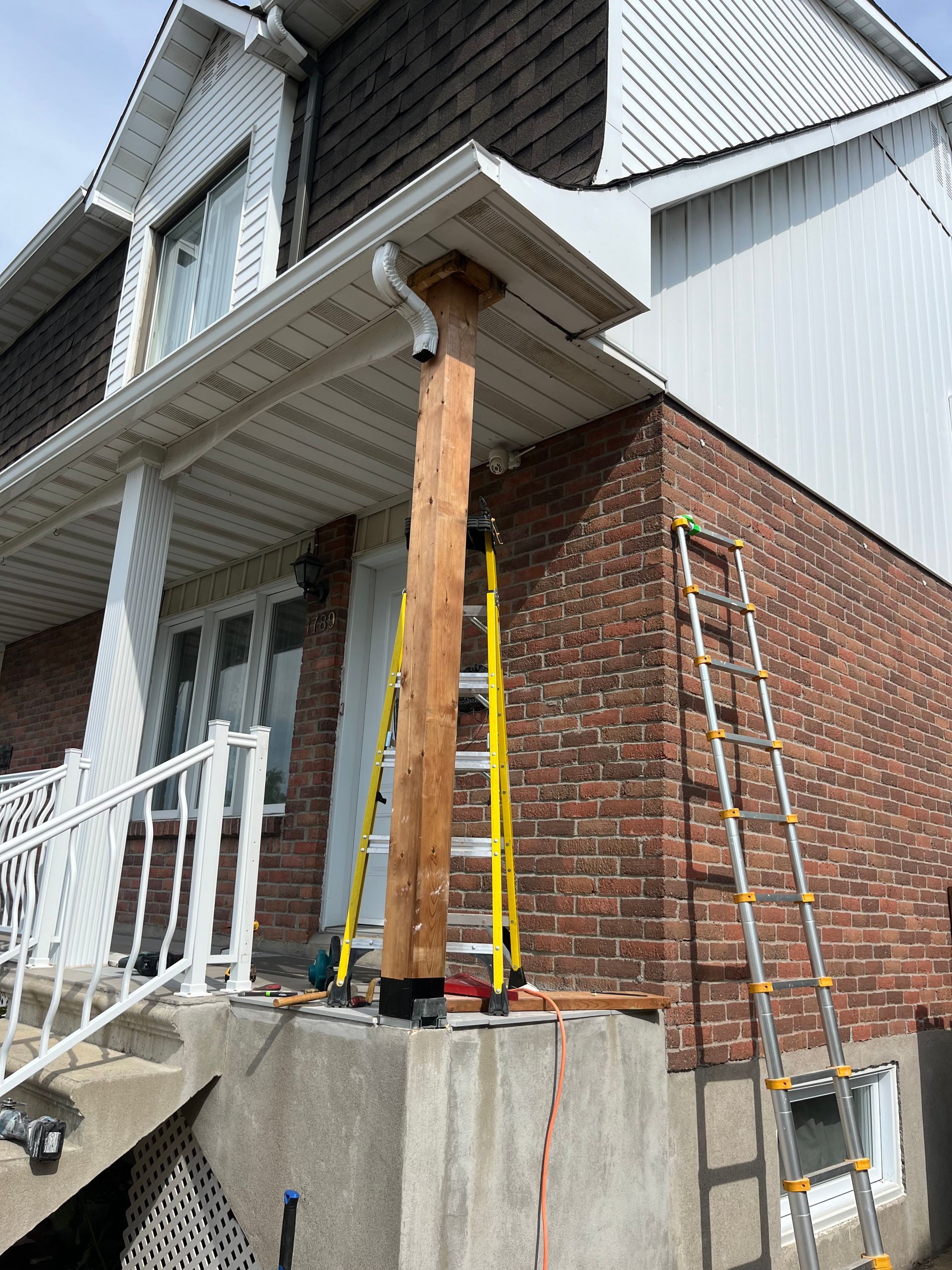 Une échelle est posée sur le côté d'une maison en briques.