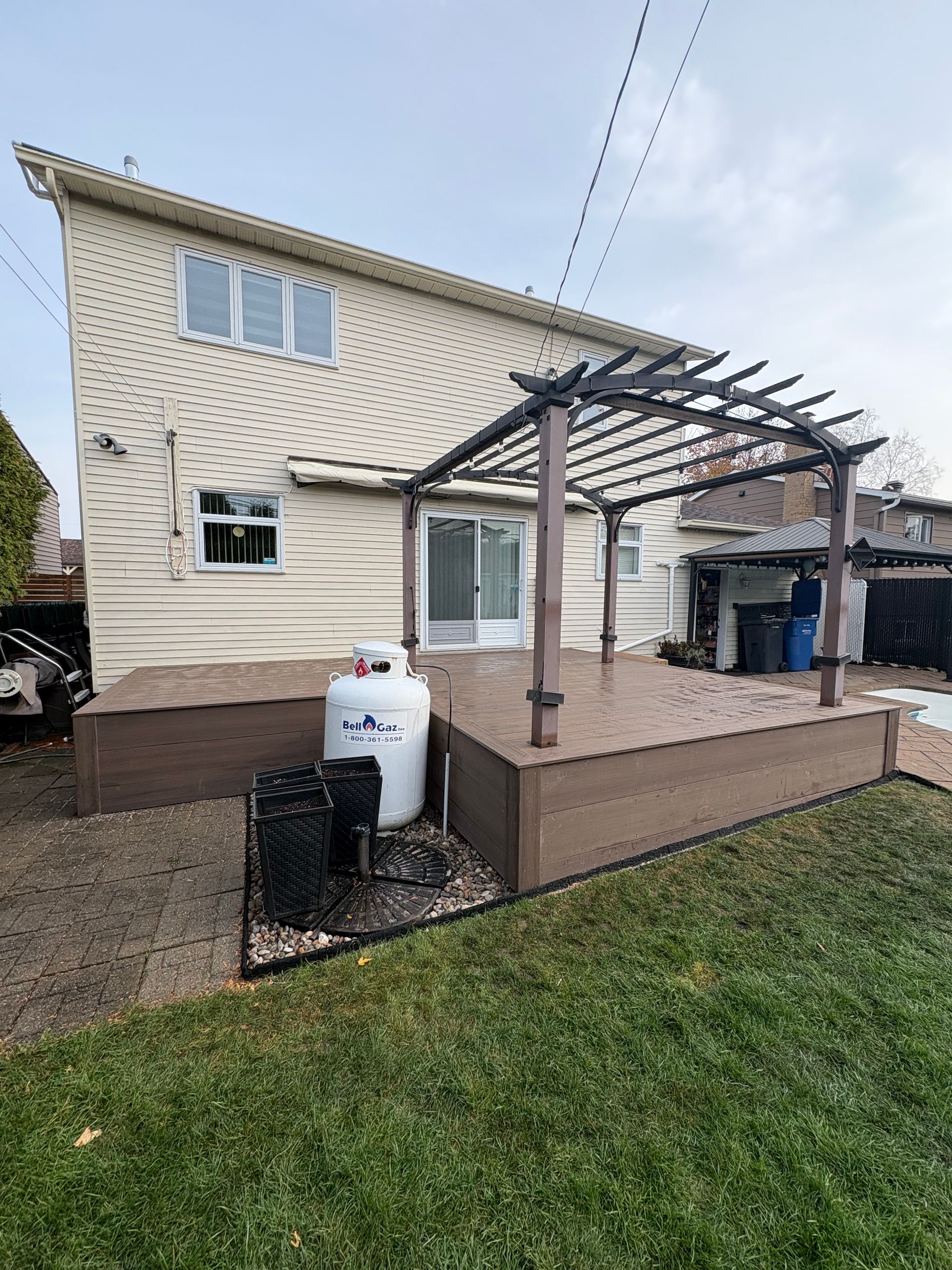 Une maison avec une terrasse et un réservoir de propane dans la cour arrière.