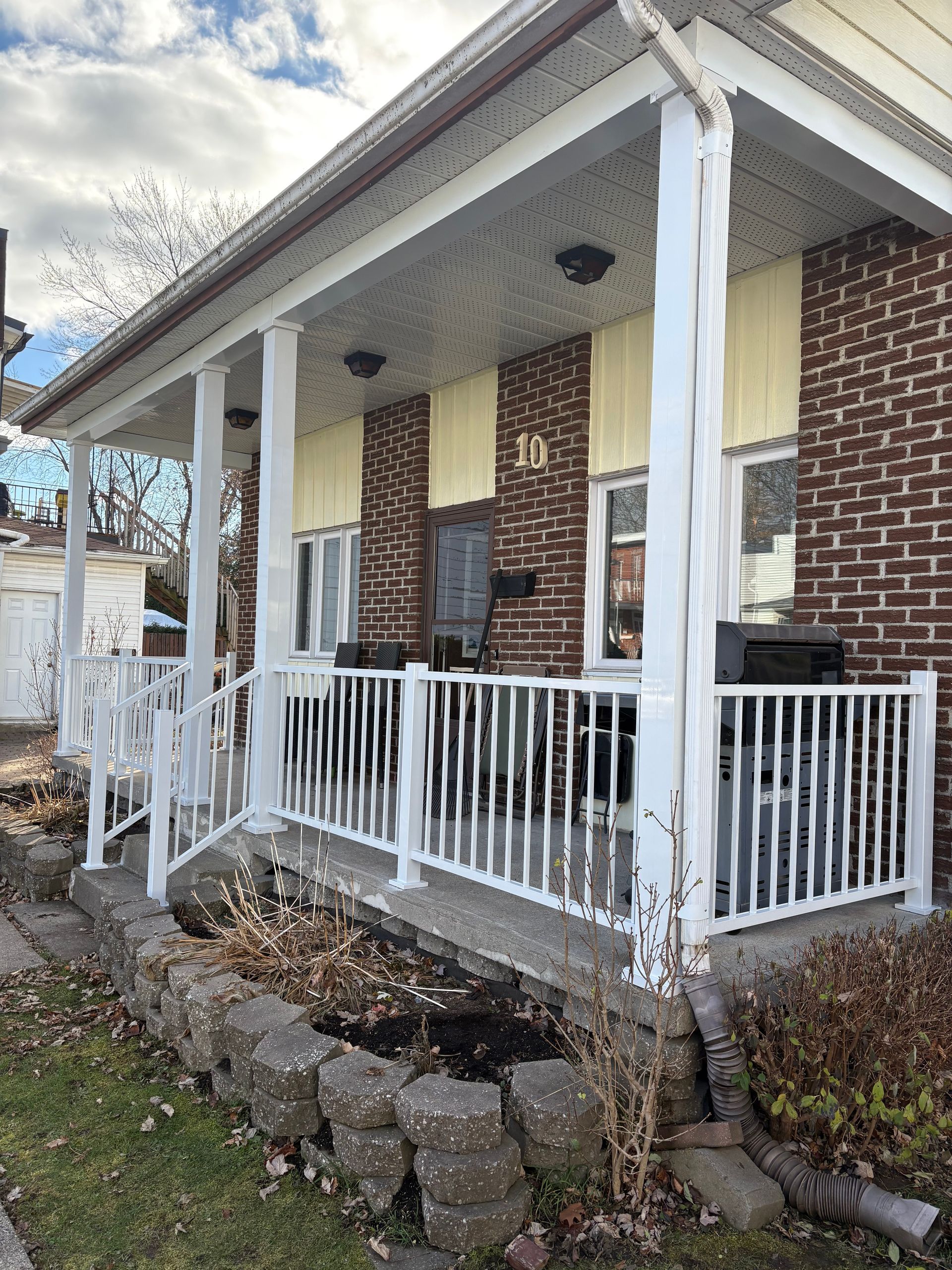 Une maison en briques avec un porche et une balustrade blanche.