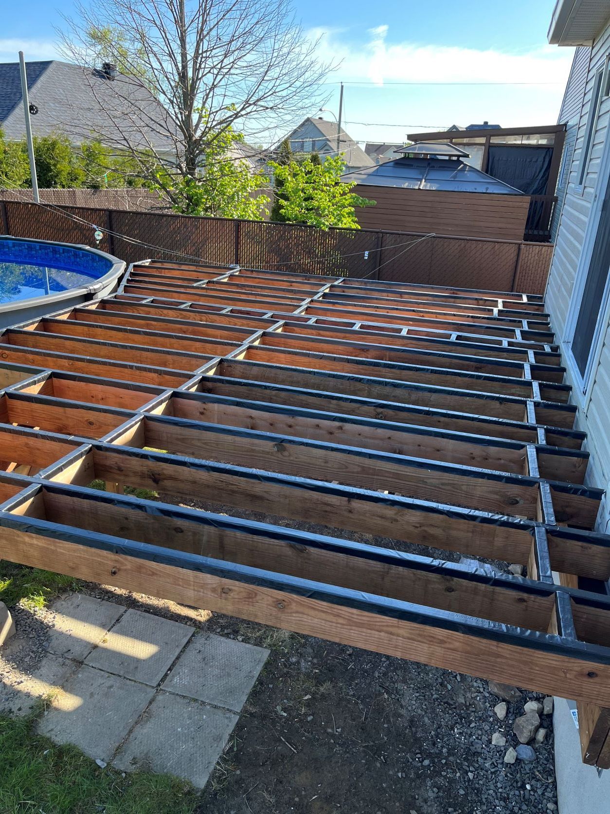 Une terrasse en bois est en cours de construction à côté d'une piscine.