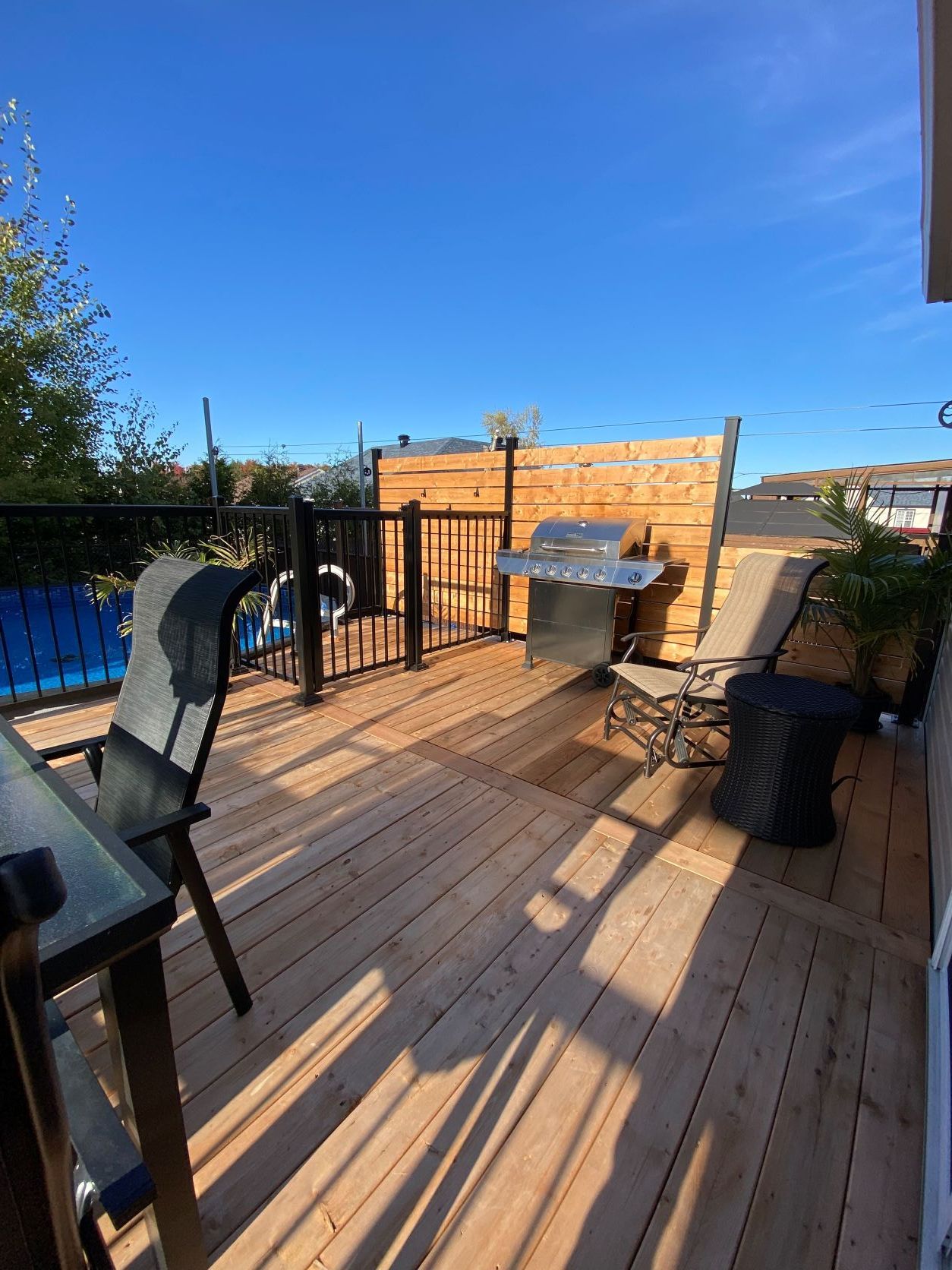 Une terrasse en bois avec une table et des chaises et un barbecue.
