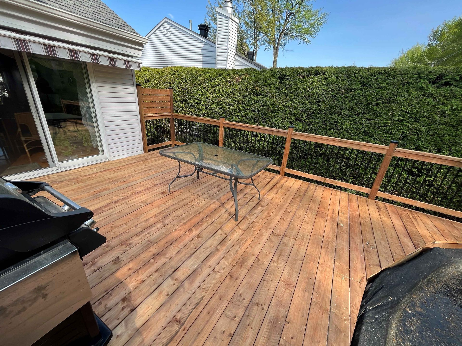 Une terrasse en bois avec une table et un barbecue dessus