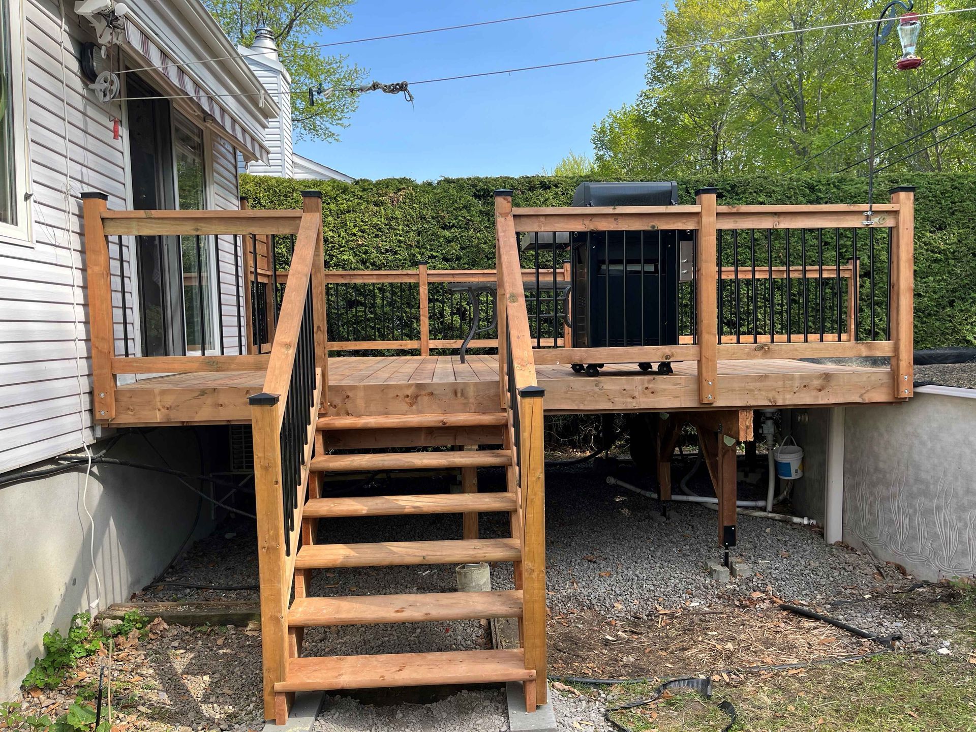 Une terrasse en bois avec des escaliers qui y mènent se trouve devant une maison.