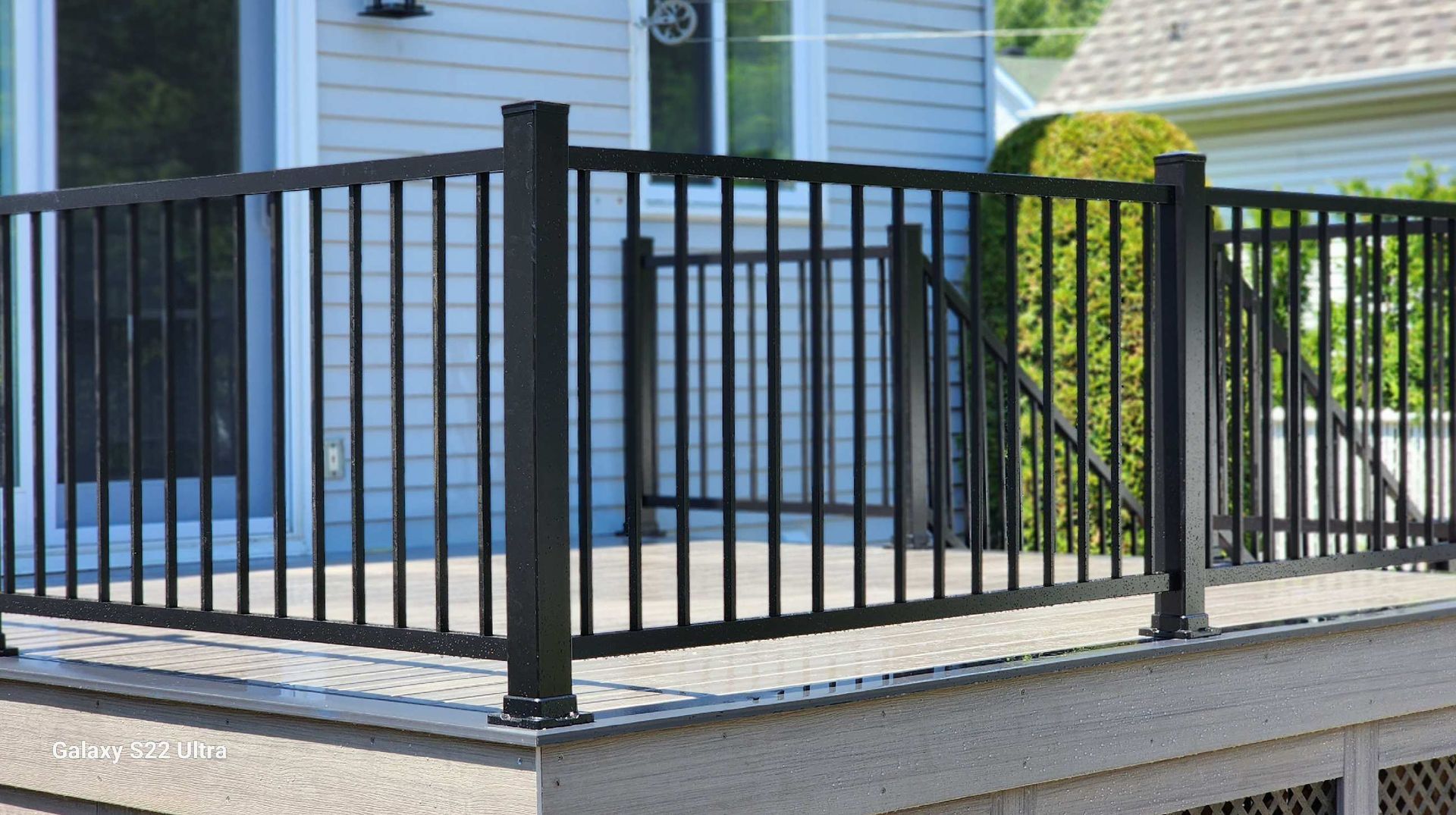 Une clôture noire entoure une terrasse devant une maison.