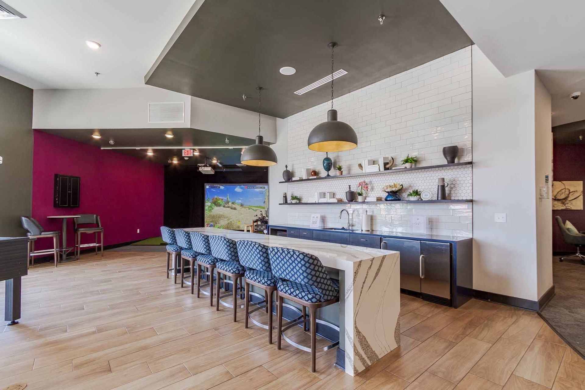 A modern communal kitchen area with a large island, bar stools, and decorative shelving.