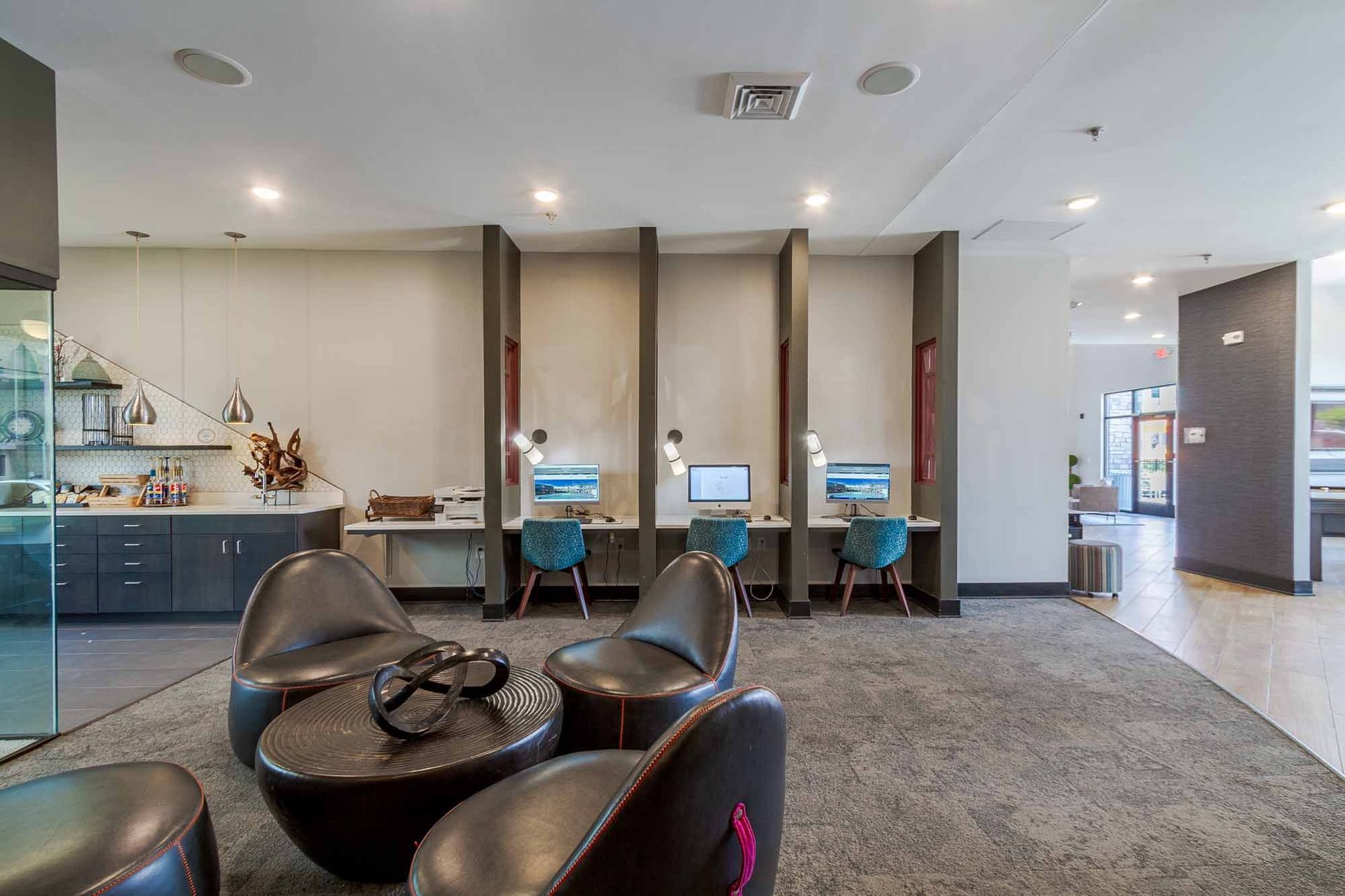 Modern co-working space with computer desks, chairs, and seating area with a small coffee table.