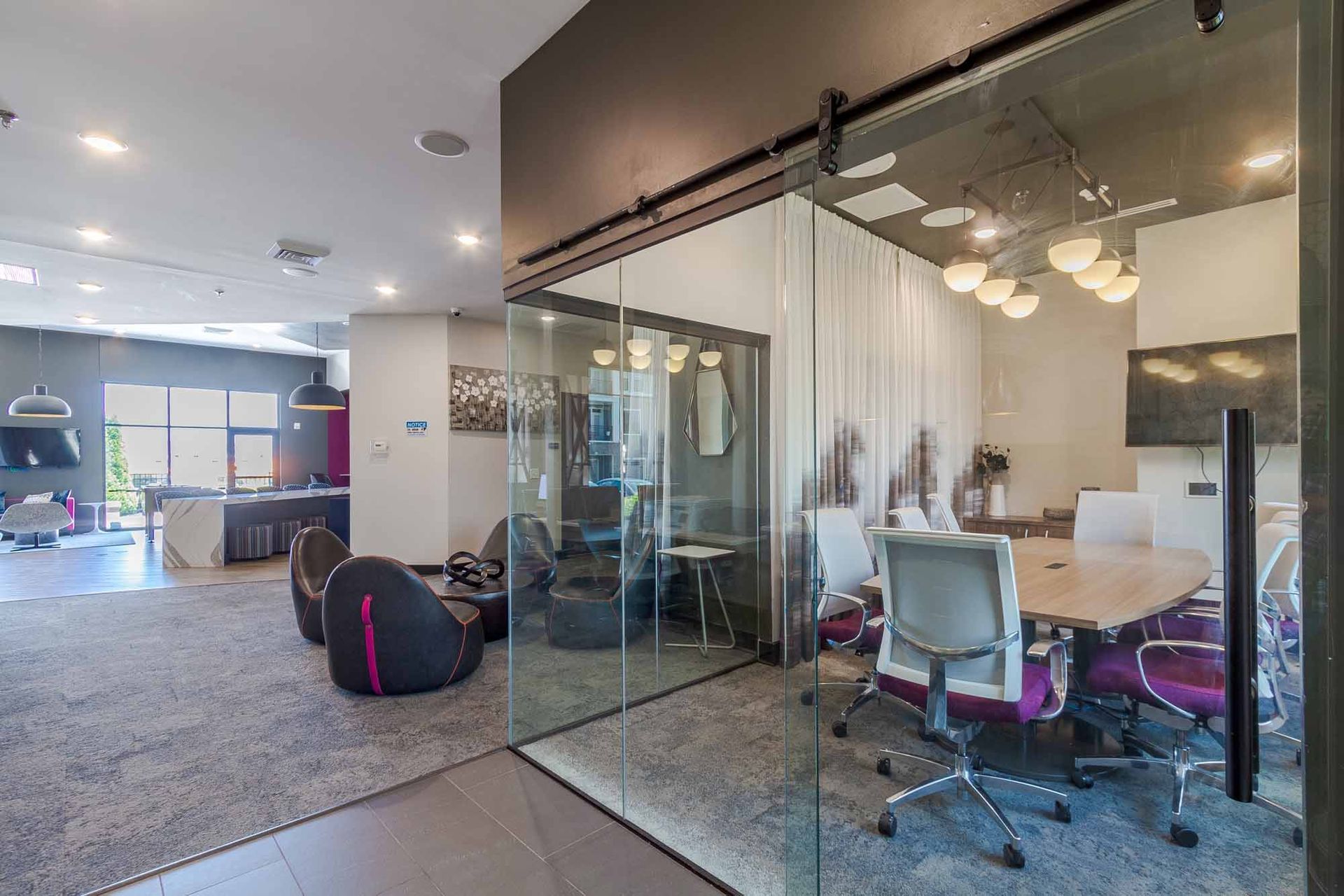 Modern office space with a glass-walled conference room, lounge area, and a pool table.