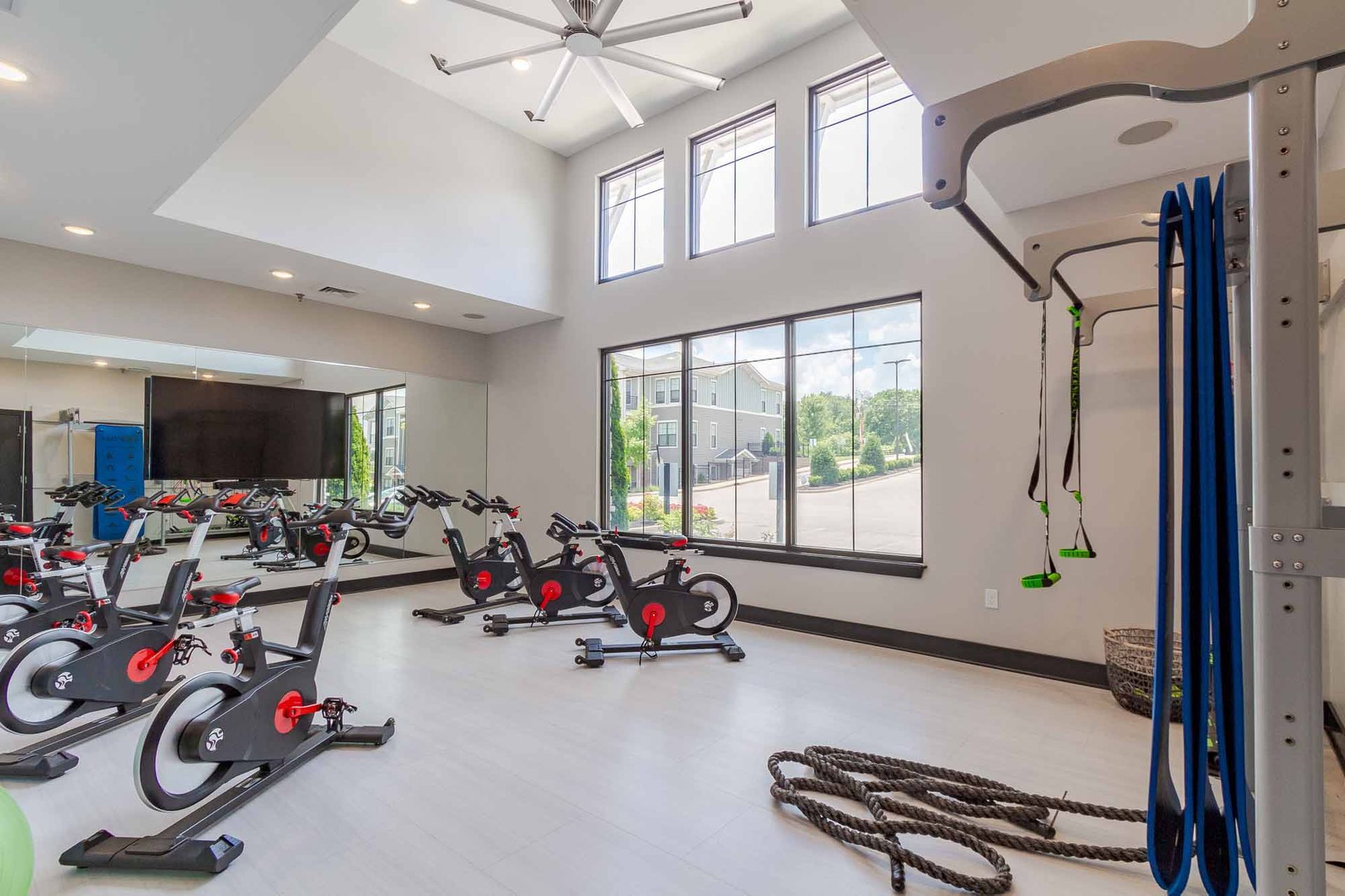 Spin cycle bikes in a gym with large windows and a mirror.