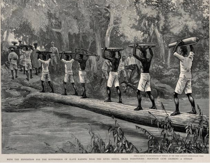 Nigerian porters carrying gun parts across Benue river in a British expedition to suppress slavery