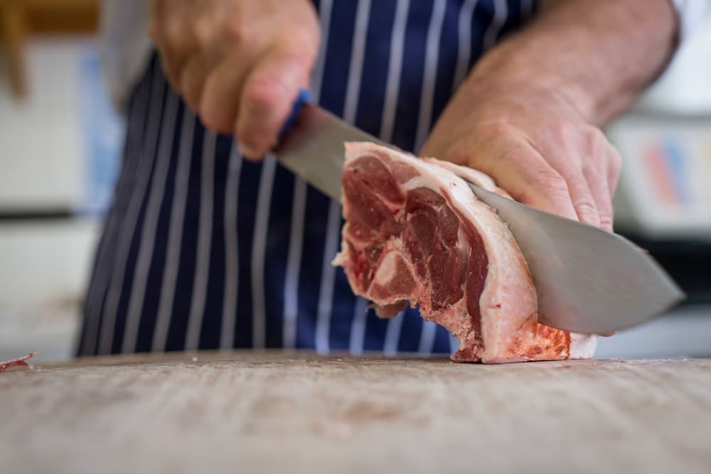 A Person Is Cutting a Piece of Meat on A Cutting Board — Prime Meats NT in Coconut Grove, NT