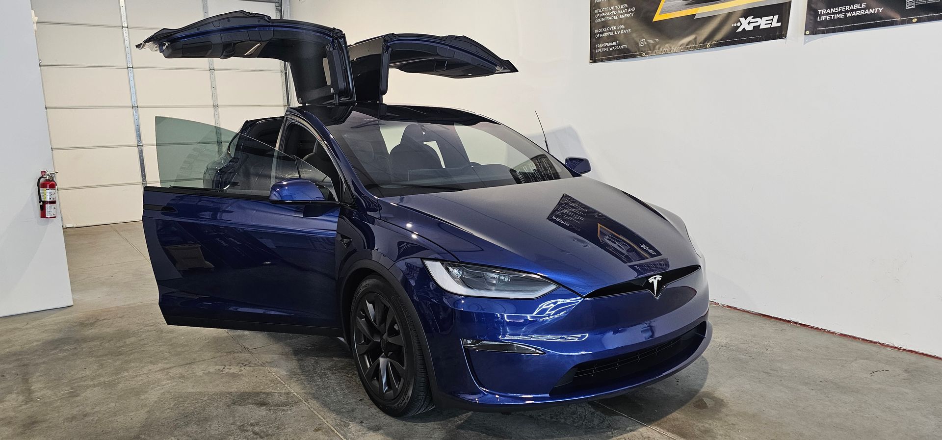 A man is applying a protective film to the side of a car.