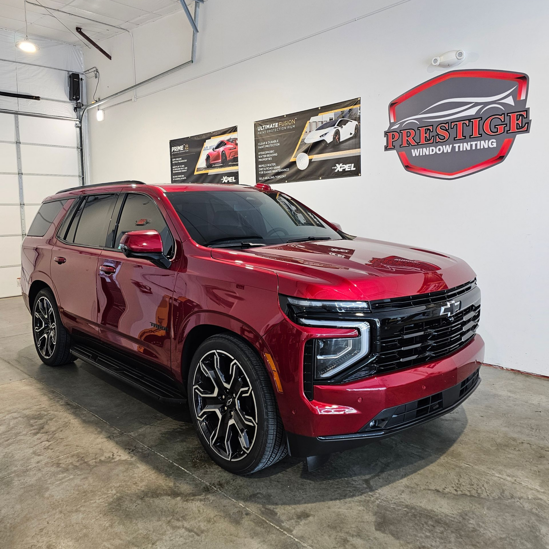 A person is cleaning the windshield of a blue car.
