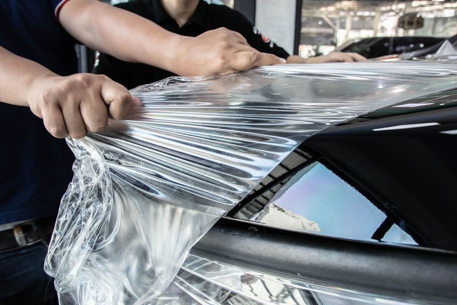 A man is wrapping a car with plastic wrap.