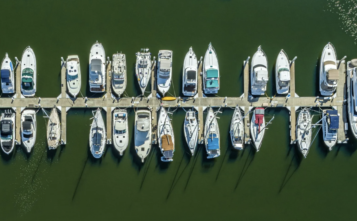 A row of boats are docked in a marina.