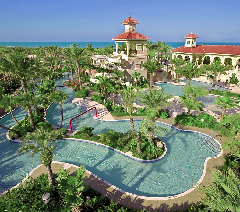 An aerial view of a large swimming pool surrounded by palm trees