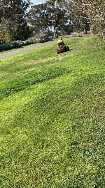 A Person Is Using A Lawn Mower To Cut Grass — Hayman Acres Garden Services In Undera, VIC