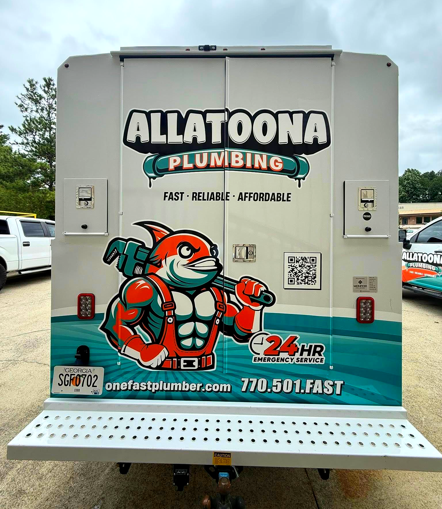 Back of Allatoona Plumbing truck with shark mascot and logo. White and teal with a website and phone number.