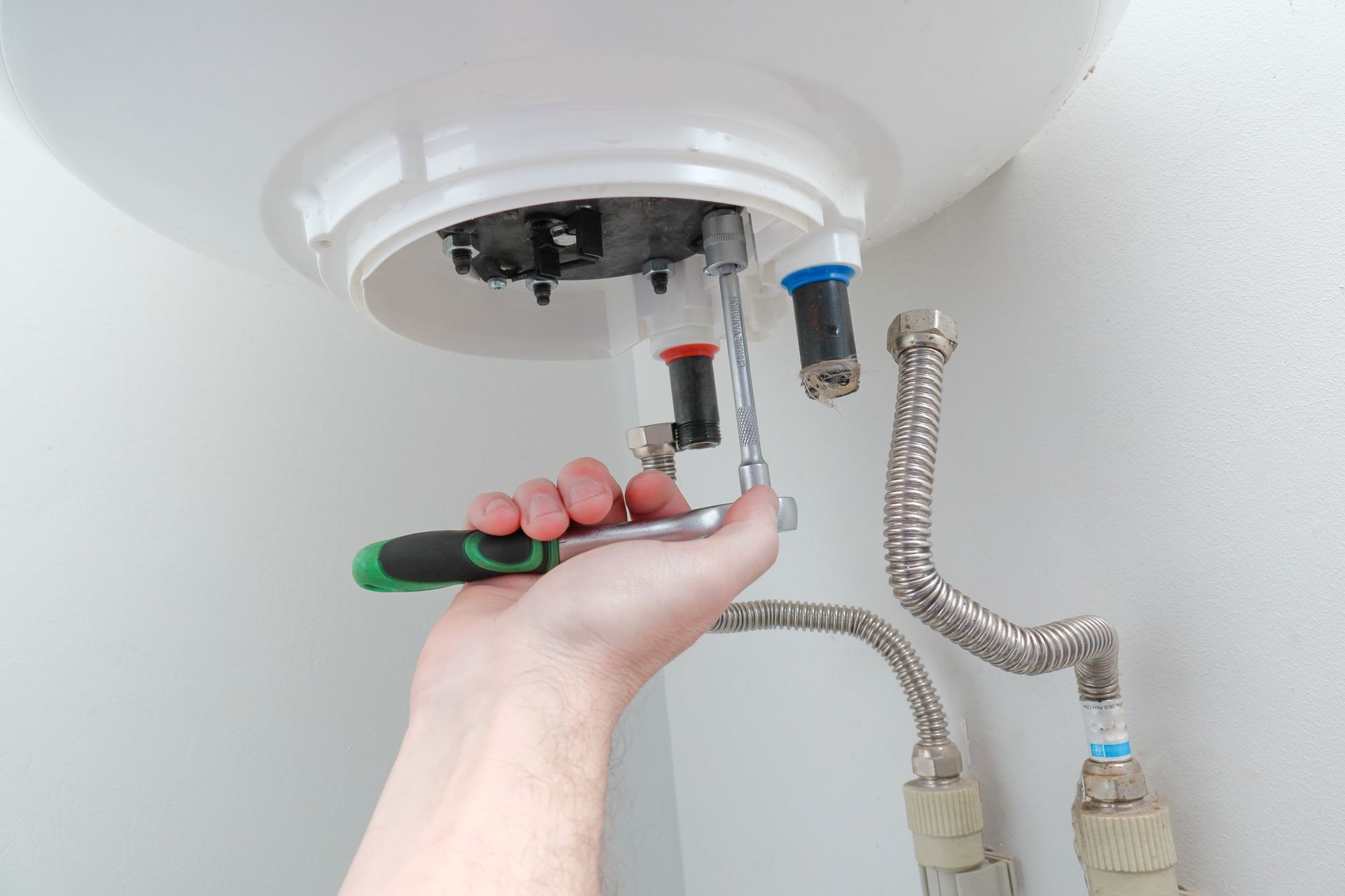 Hand tightening a nut on a water heater's valve assembly.