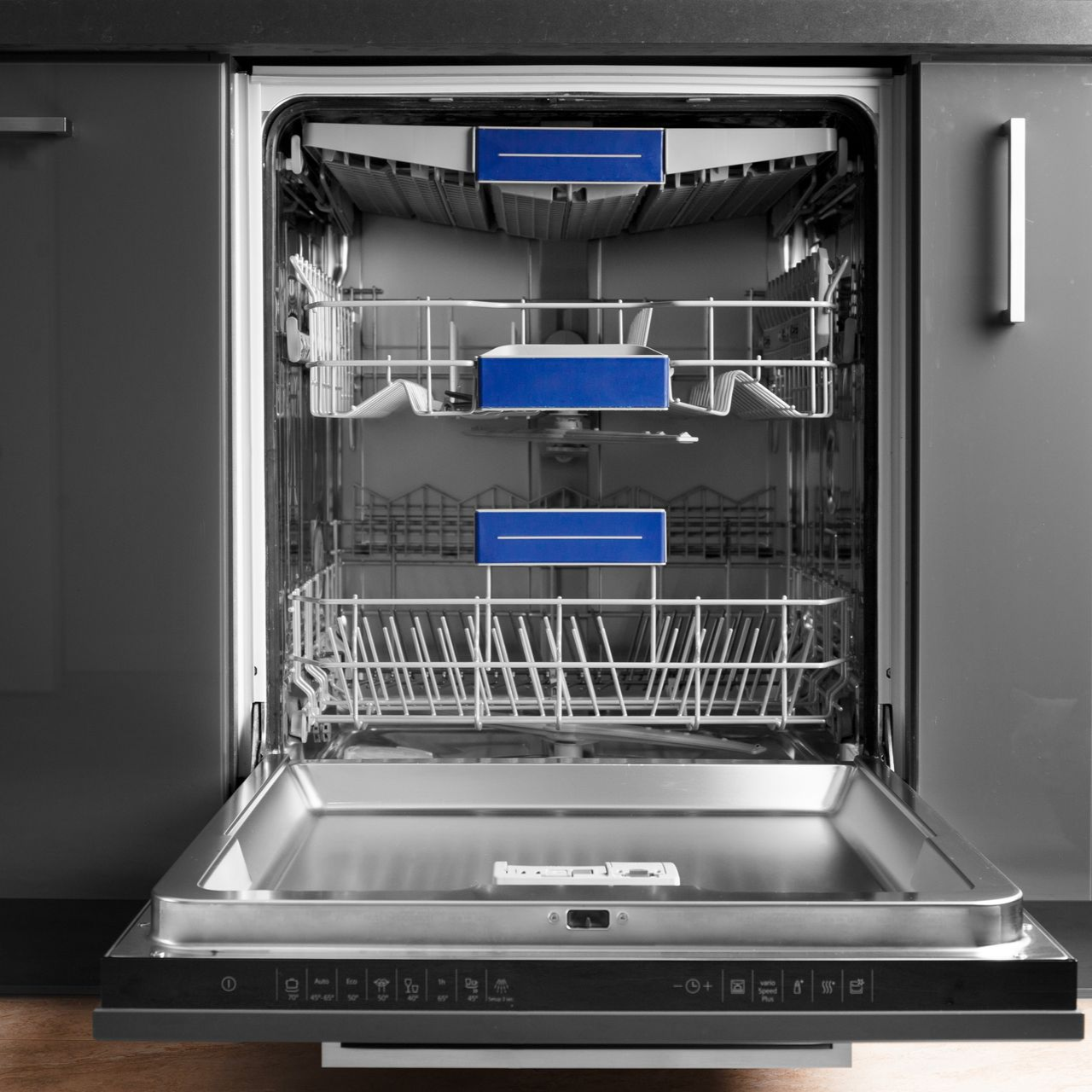 Open dishwasher with blue cleaning product boxes in each rack.