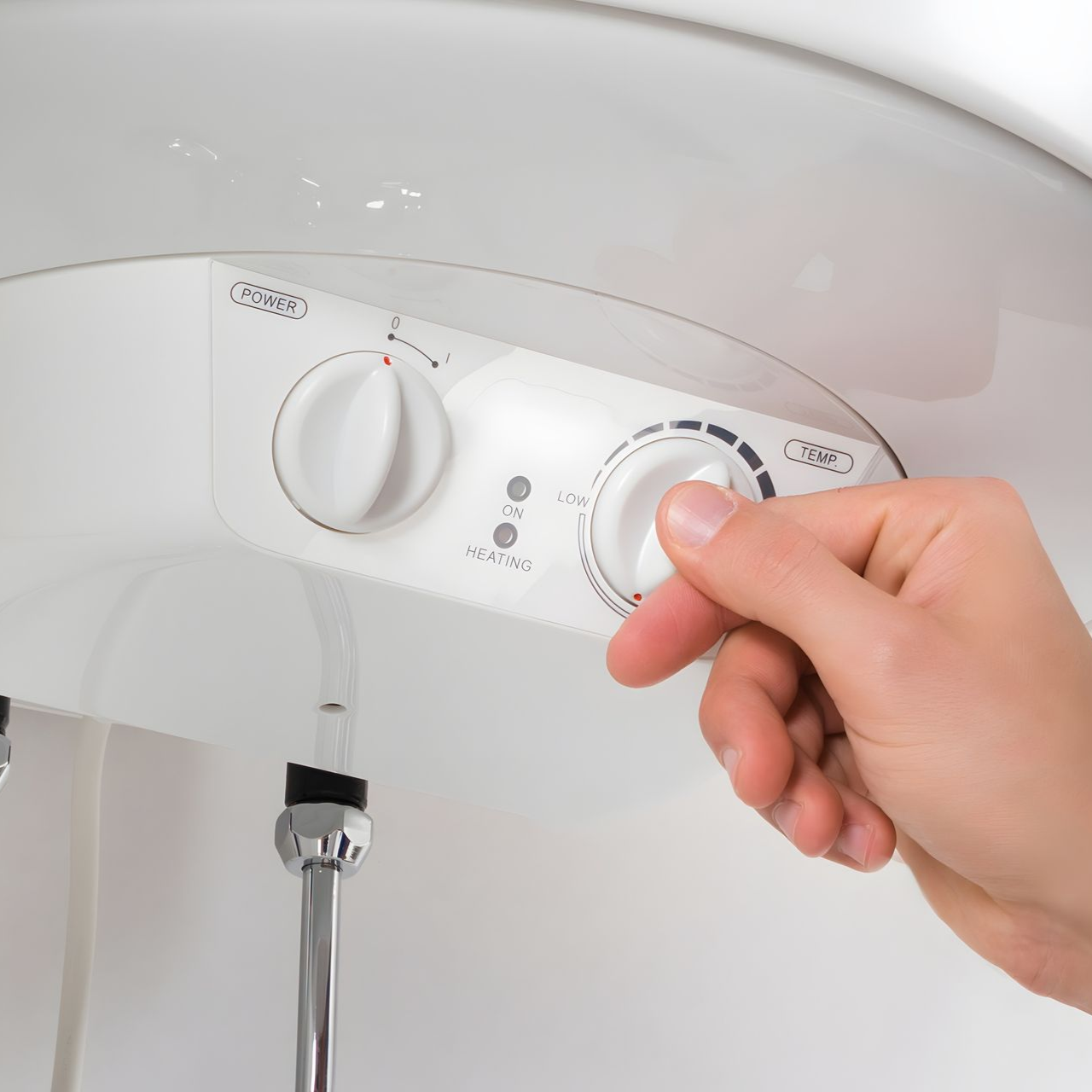 Hand turning a dial on a white water heater, adjusting the temperature.