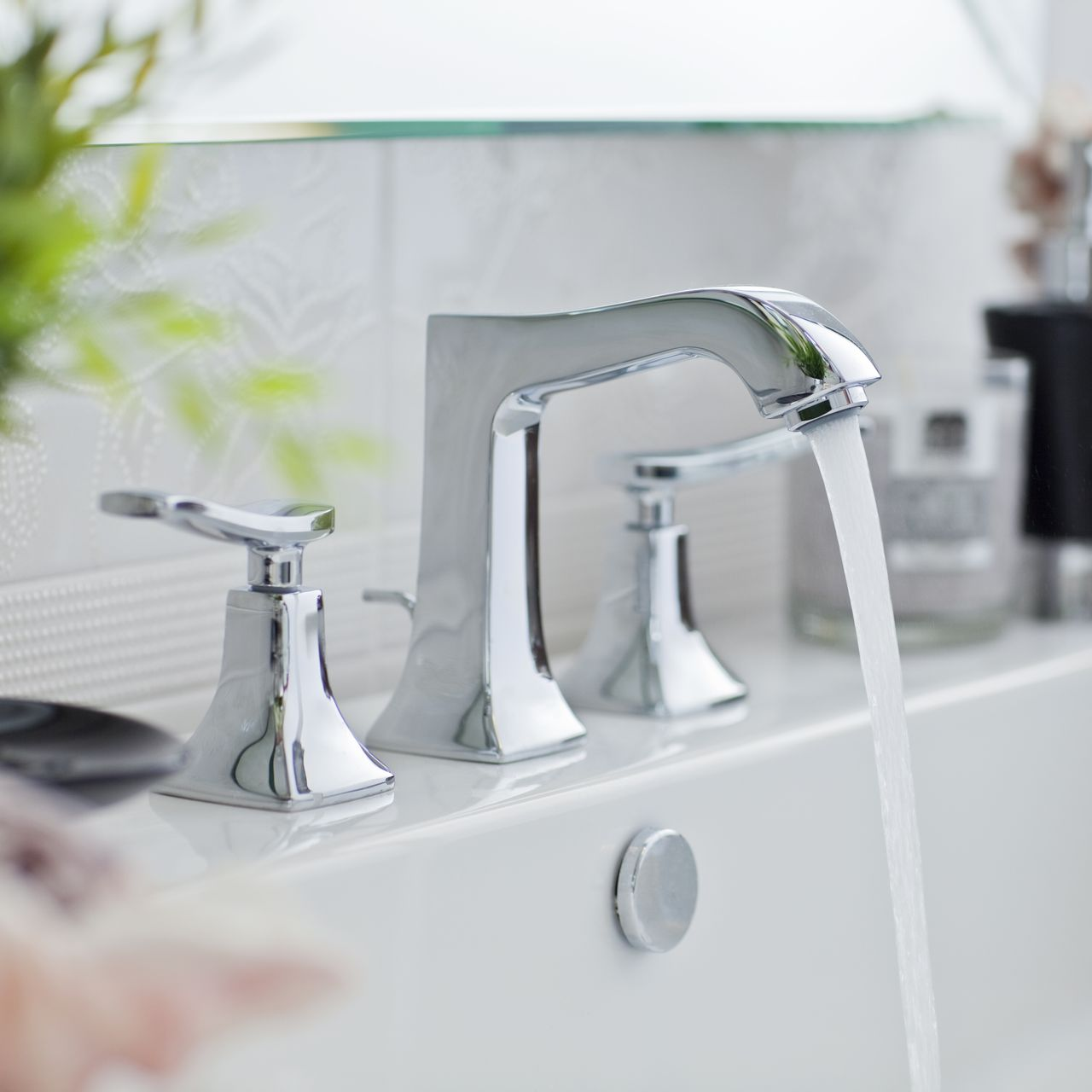 Chrome faucet with running water in a white sink.
