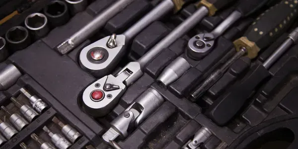 Close-up of a toolbox with various metal hand tools arranged inside.
