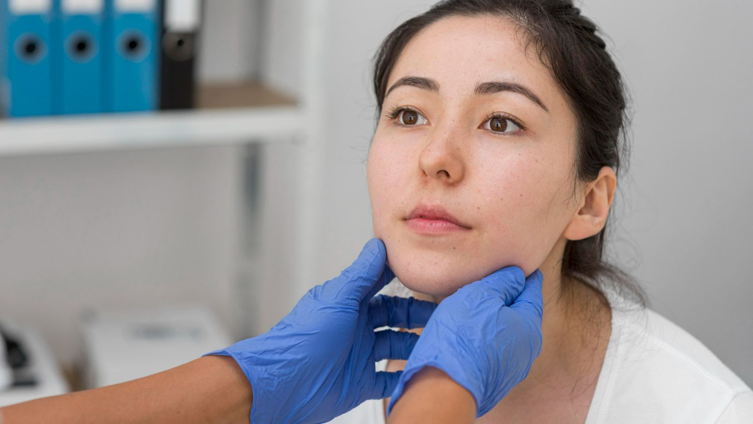 A woman is having her throat examined by a doctor.