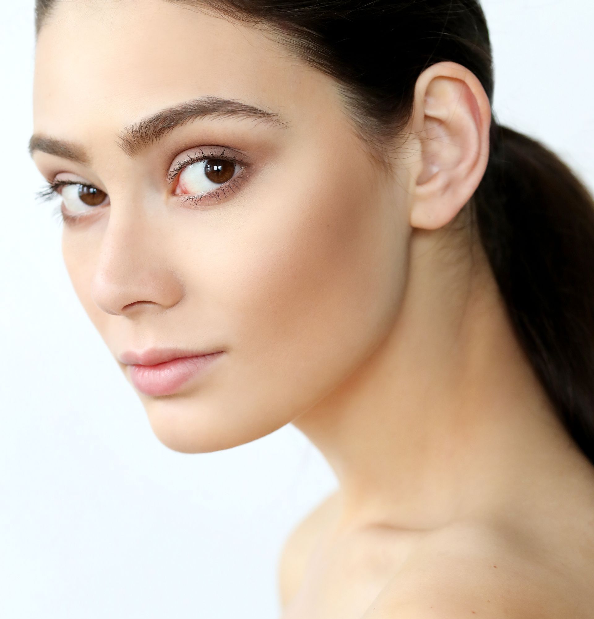 A close up of a woman 's face with her hair in a ponytail.