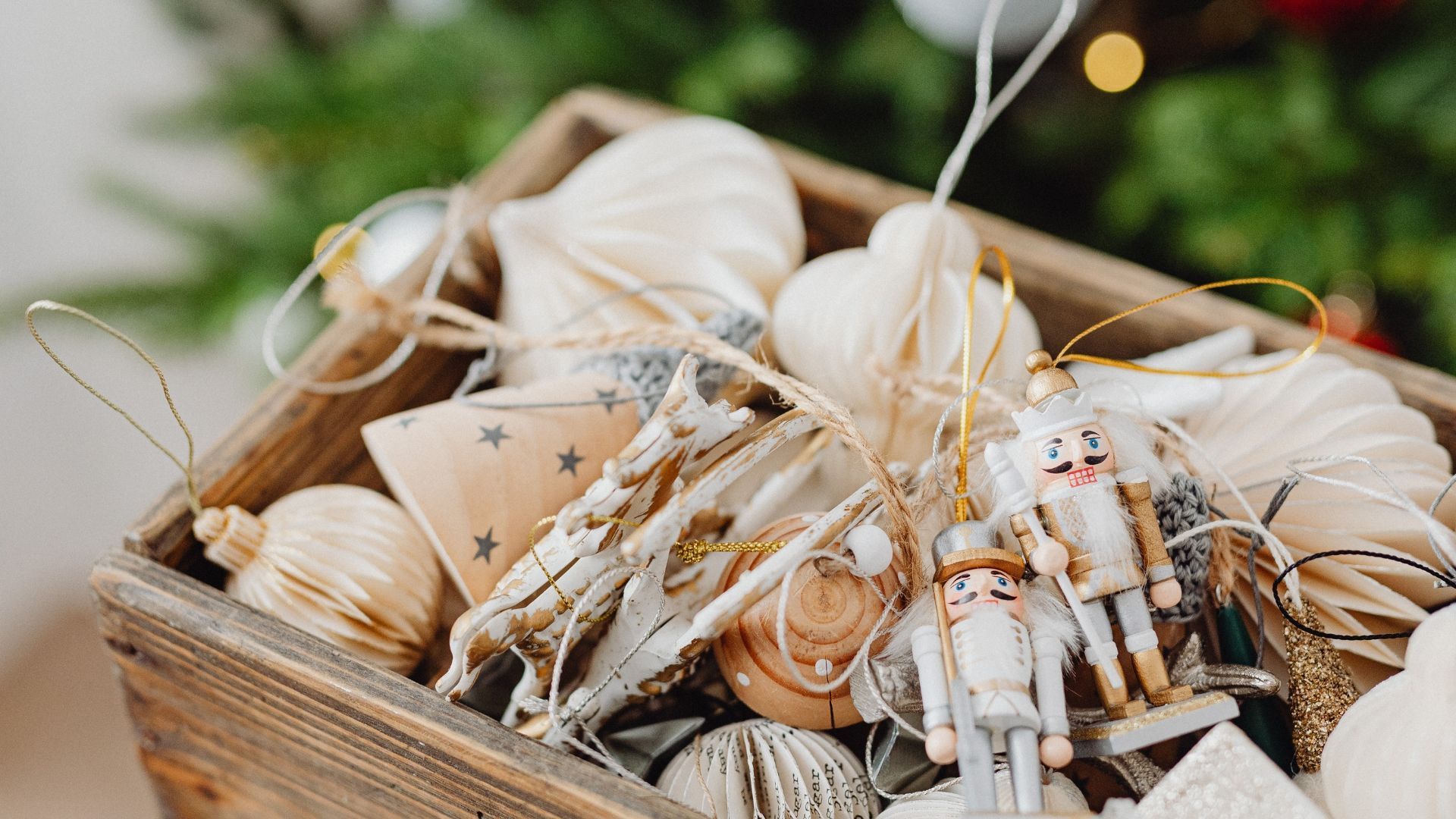Tray of beige and white Christmas ornaments with stars, tassels, and pinecones on a festive table