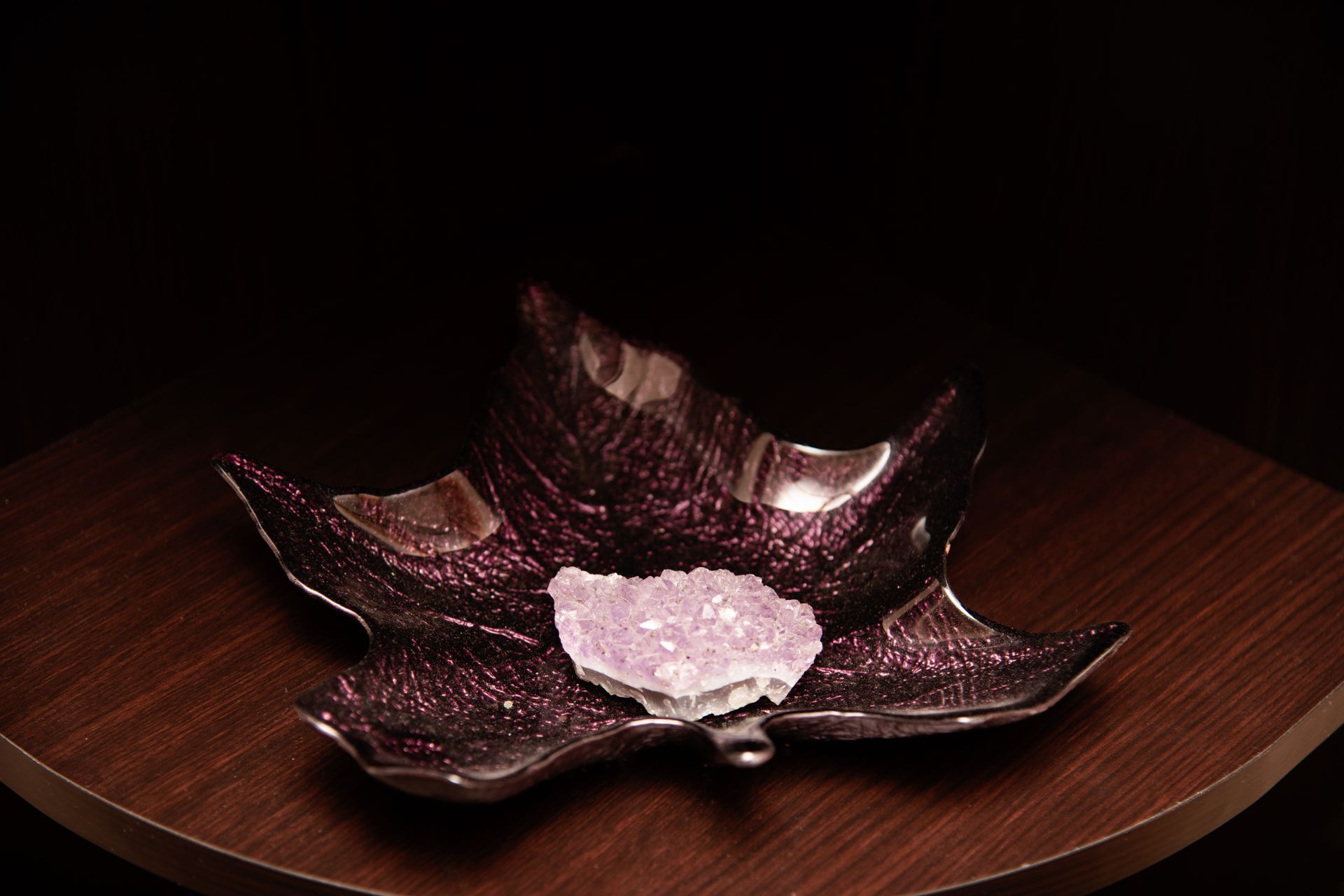 A purple leaf shaped plate with a heart in the middle on a wooden table.