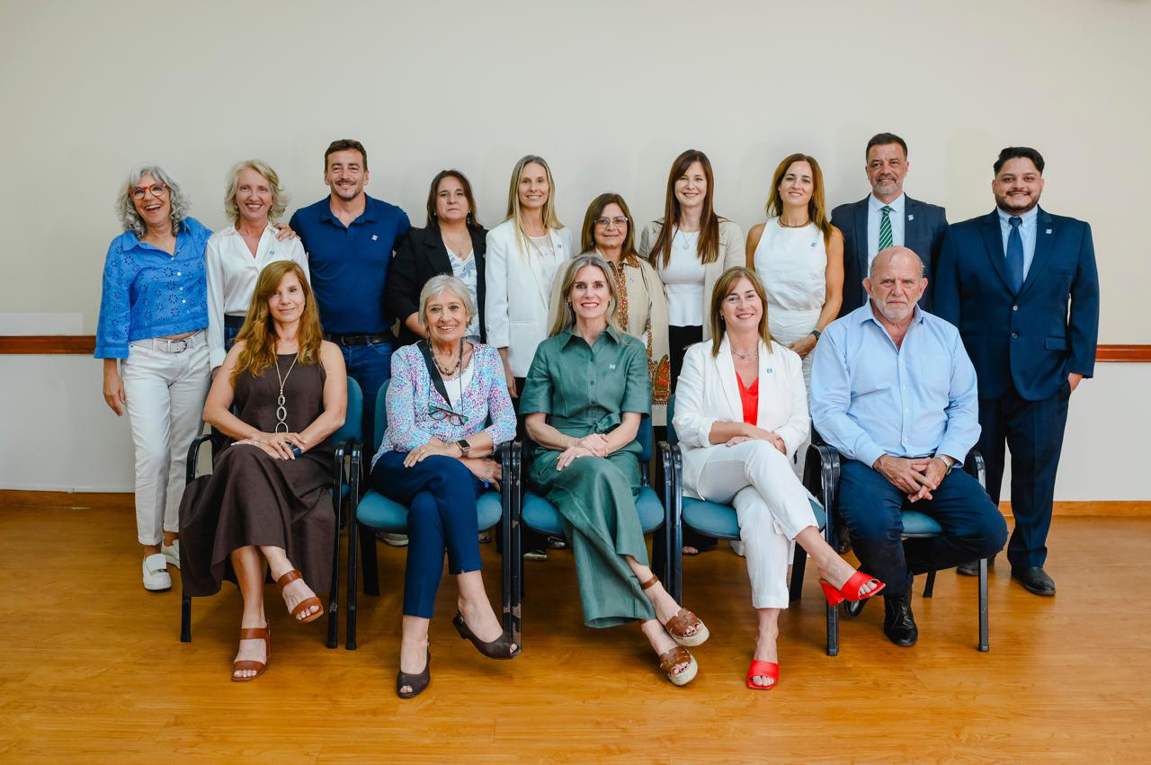 Grupo de personas posando para una foto en una habitación. Algunas sentadas, otras de pie.