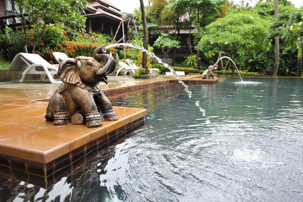 A Statue Of An Elephant Is Sitting On A Ledge Next To A Swimming Pool — Yamba Pools & Spas In Yamba, NSW